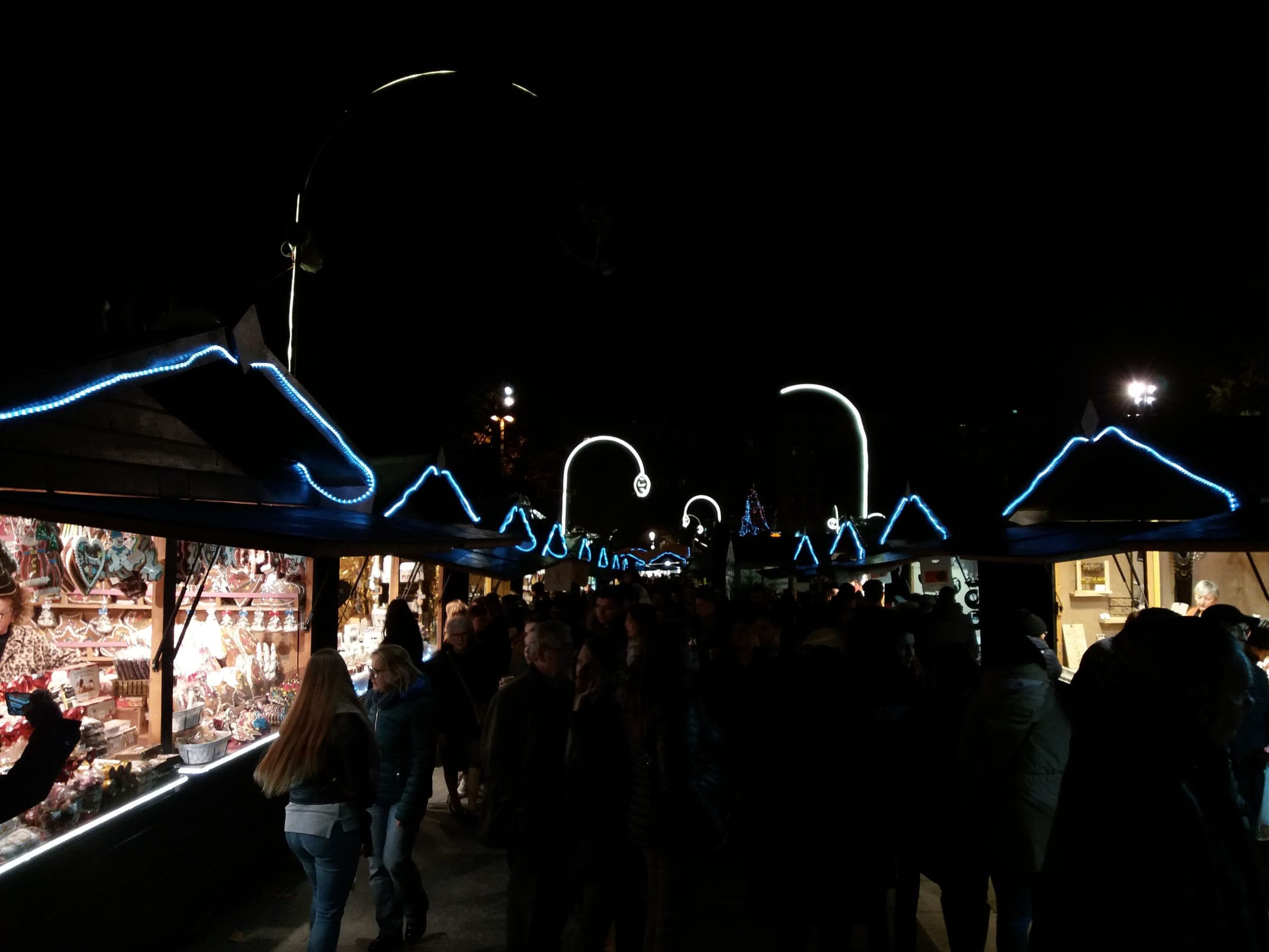 Blue light strips trace the chalet roofs over the crowded central aisle of the Place Carnot market in Lyon.