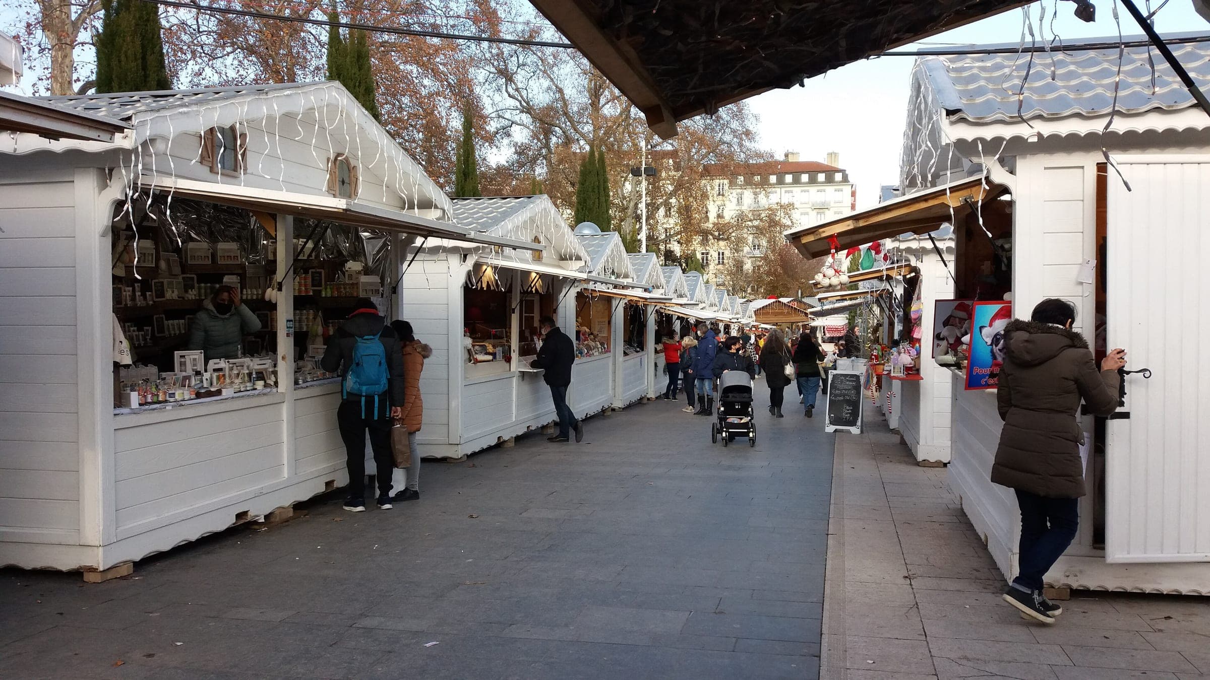 Shoppers browse a lane of white wooden chalets at the Place Carnot Christmas market in Lyon.