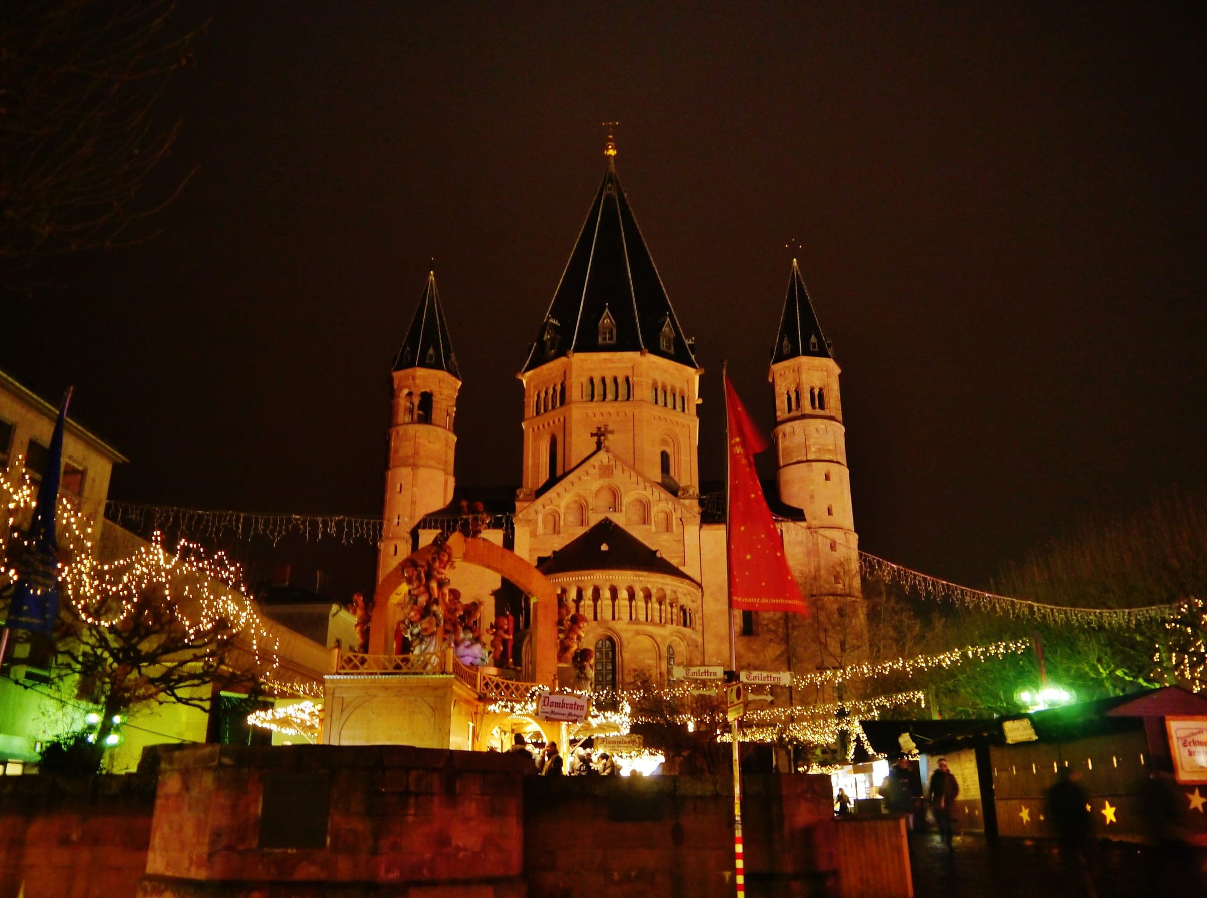 Mainz Cathedral glows at night above the strings of lights and stalls of the Christmas market.