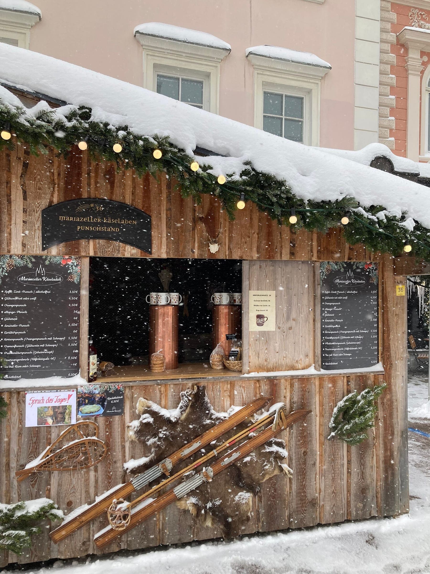 Garlands and old wooden skis decorate a snow-roofed punch stall at the Mariazell Advent market.