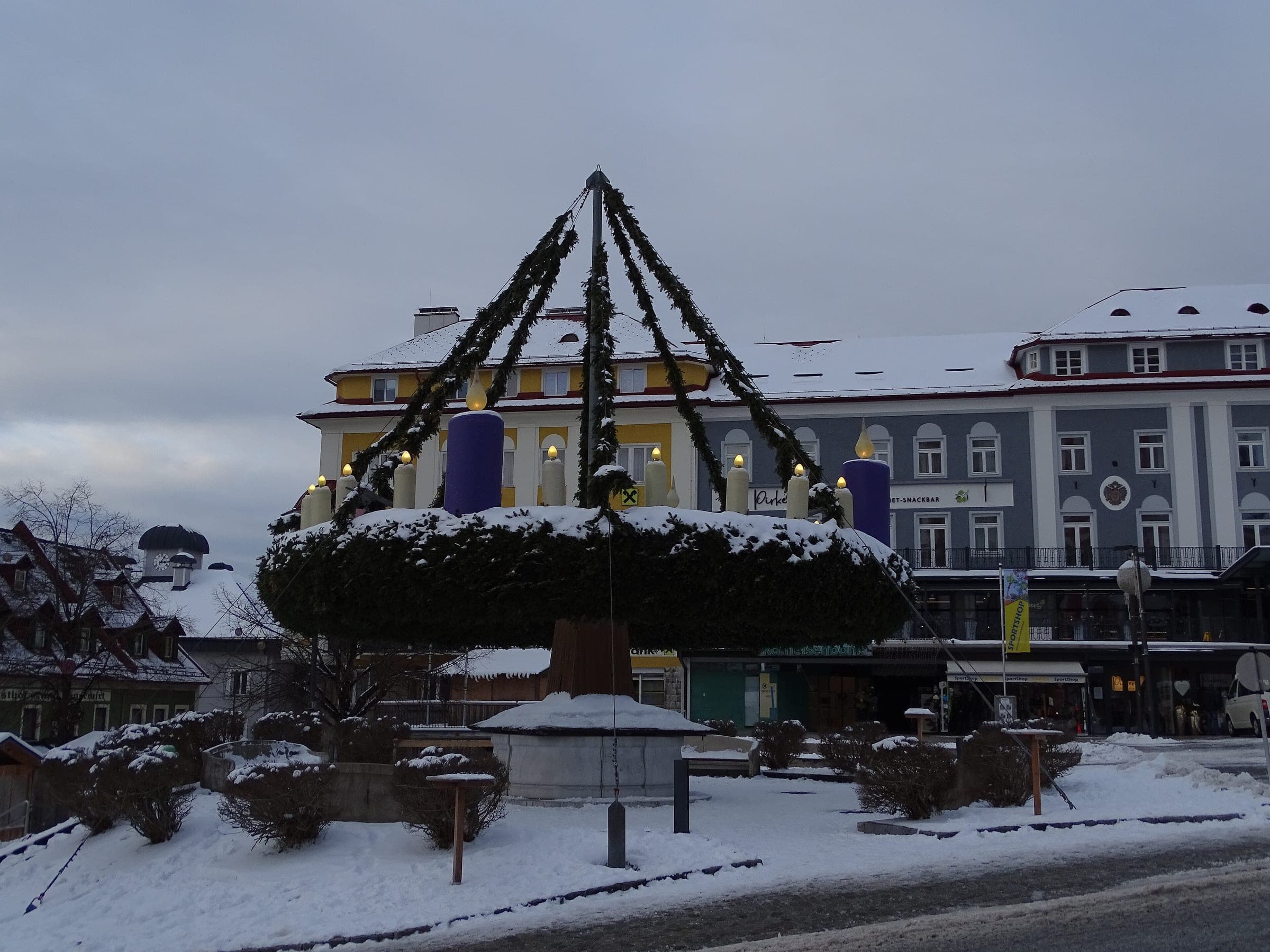 Purple candles top the giant Advent wreath on a snowy Hauptplatz in Mariazell.