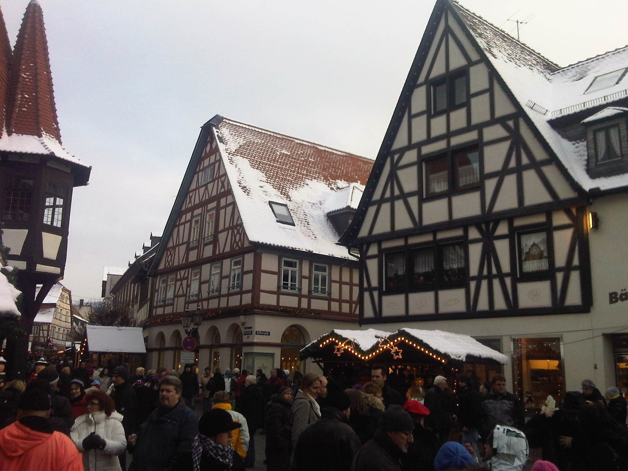 Crowds browse the stalls below snowy timber-framed gables during the Michelstadt Christmas market.