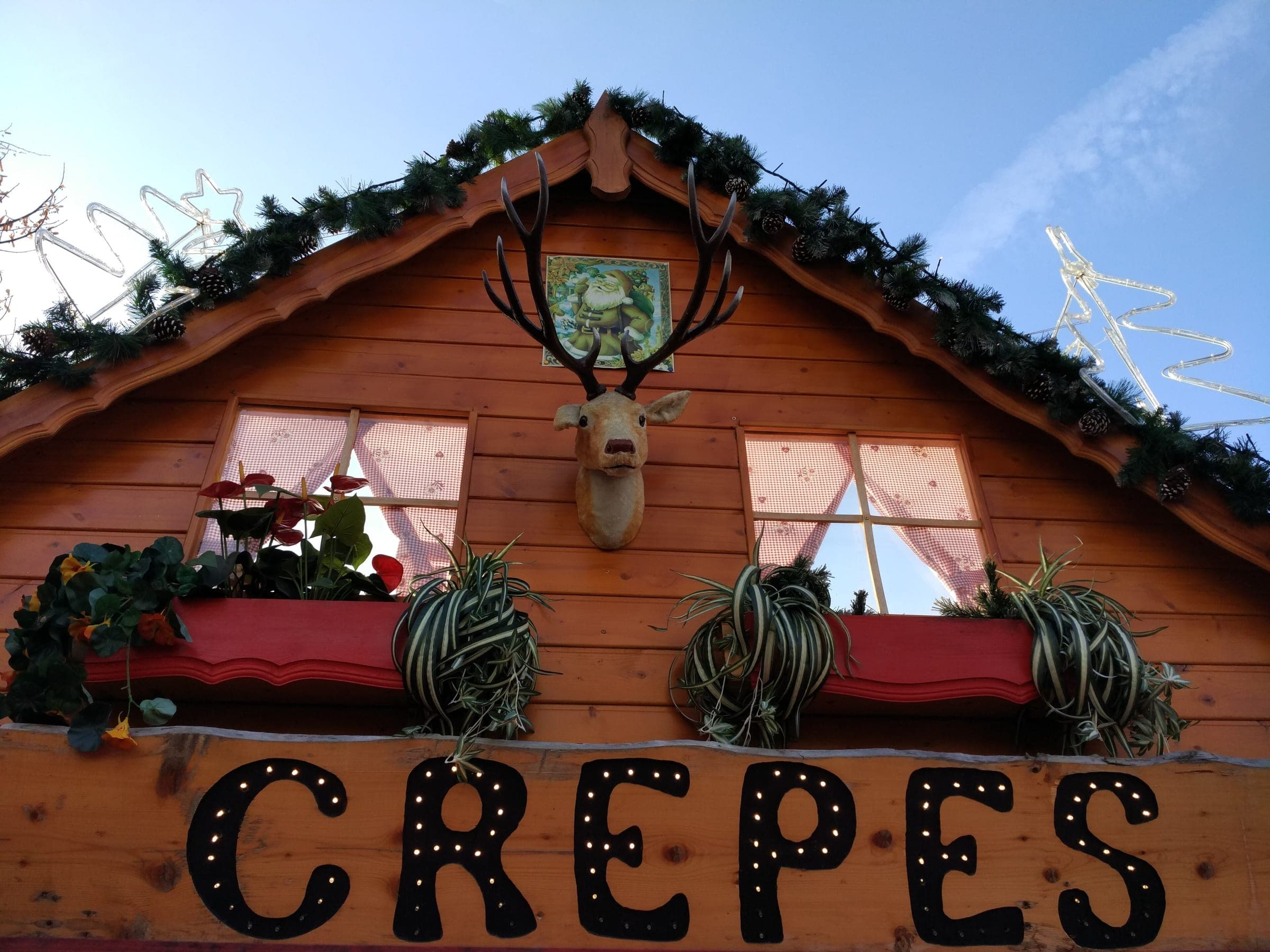 A wooden crêpe chalet at Montreux Noël carries a garland, a stag's head and lights along its roof