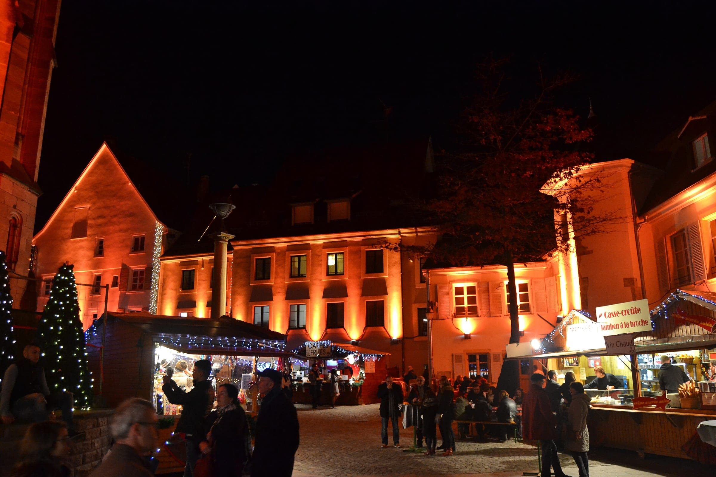 Orange light washes over the old houses and market chalets in central Mulhouse on a December night.