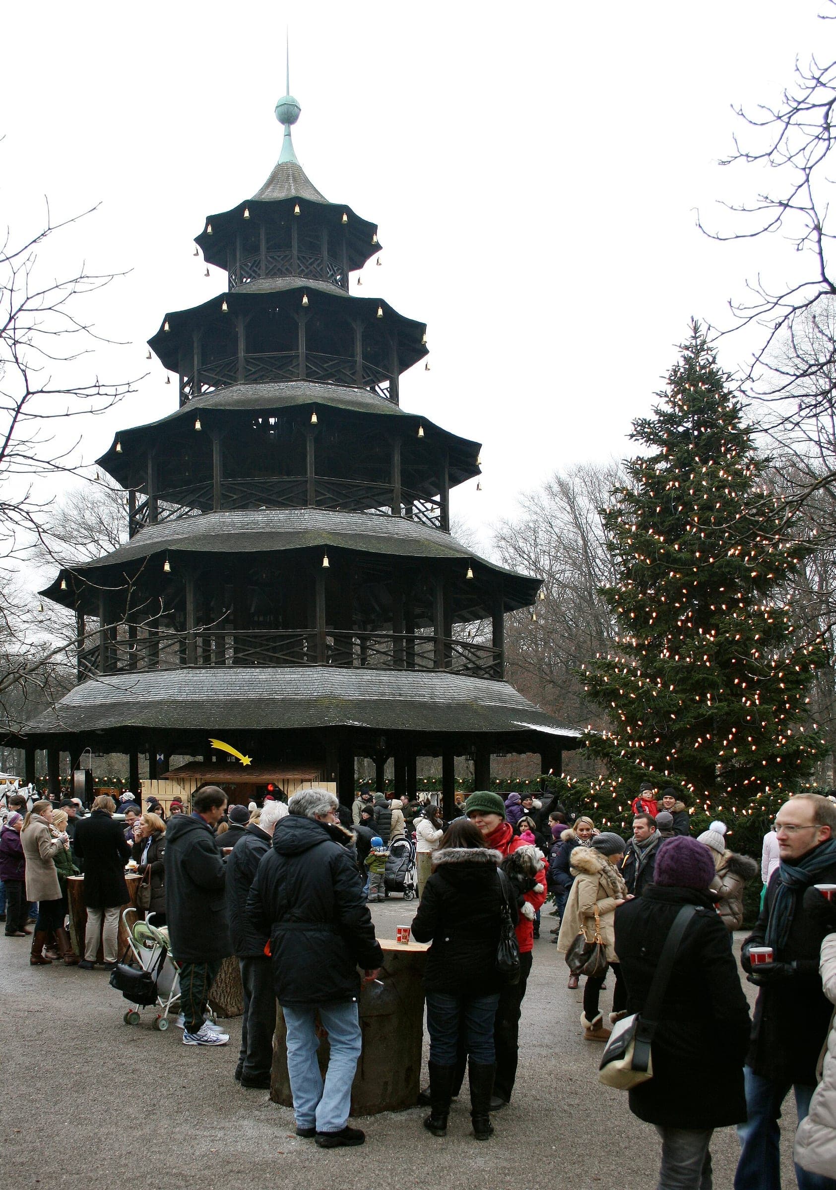 Visitors crowd the Christmas market below the wooden Chinese Tower in Munich's English Garden.