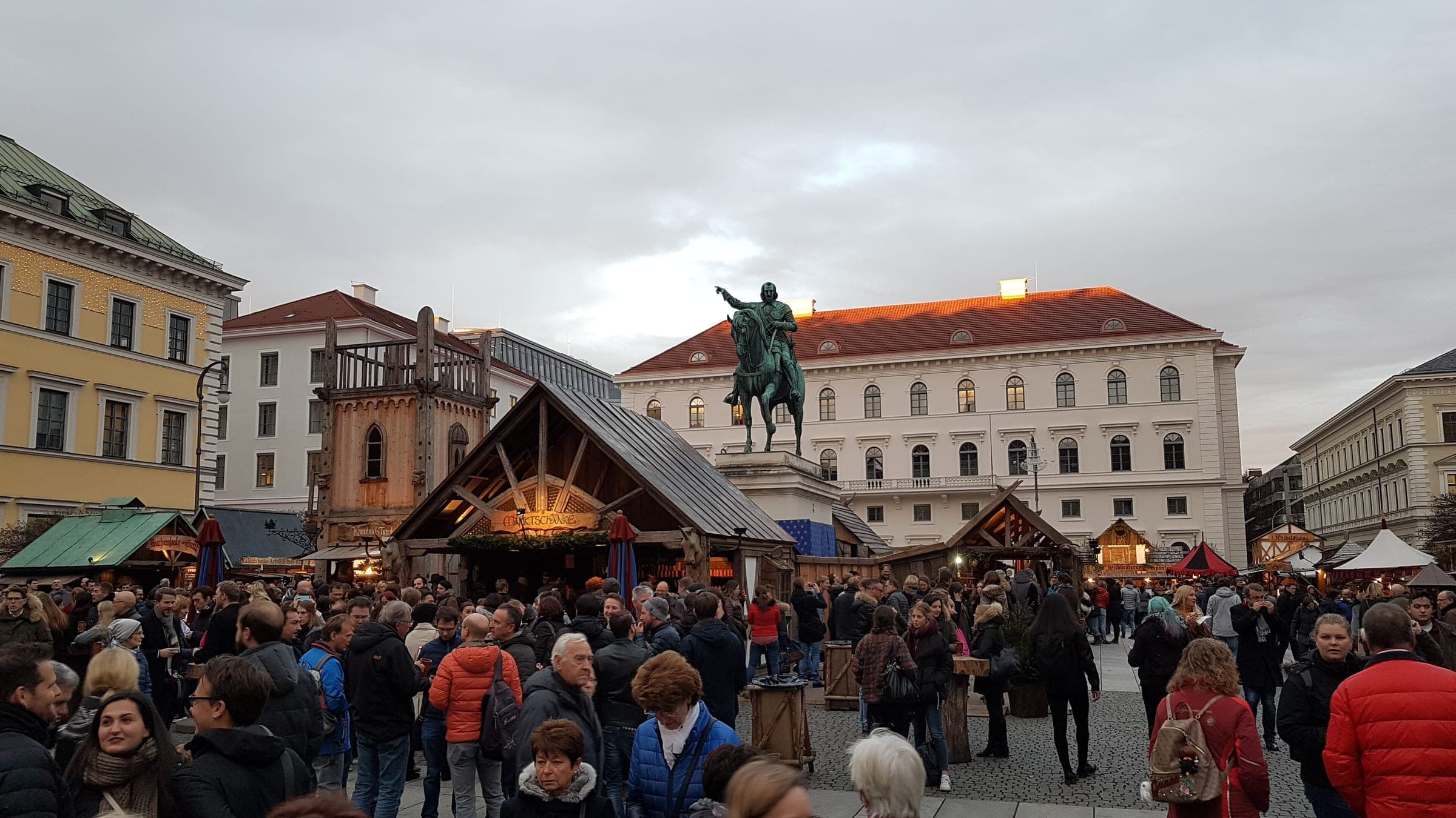 Crowds fill the medieval Advent market on Wittelsbacherplatz in Munich around the statue of Elector Maximilian I.