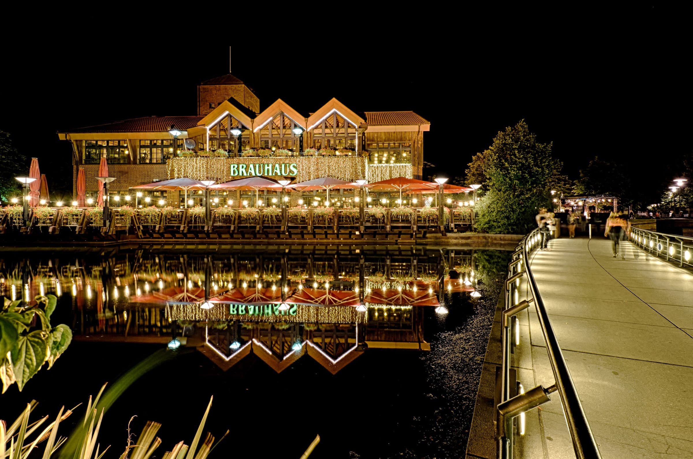 Lights from the brewpub on the CentrO Promenade in Oberhausen reflect in the harbour basin at night