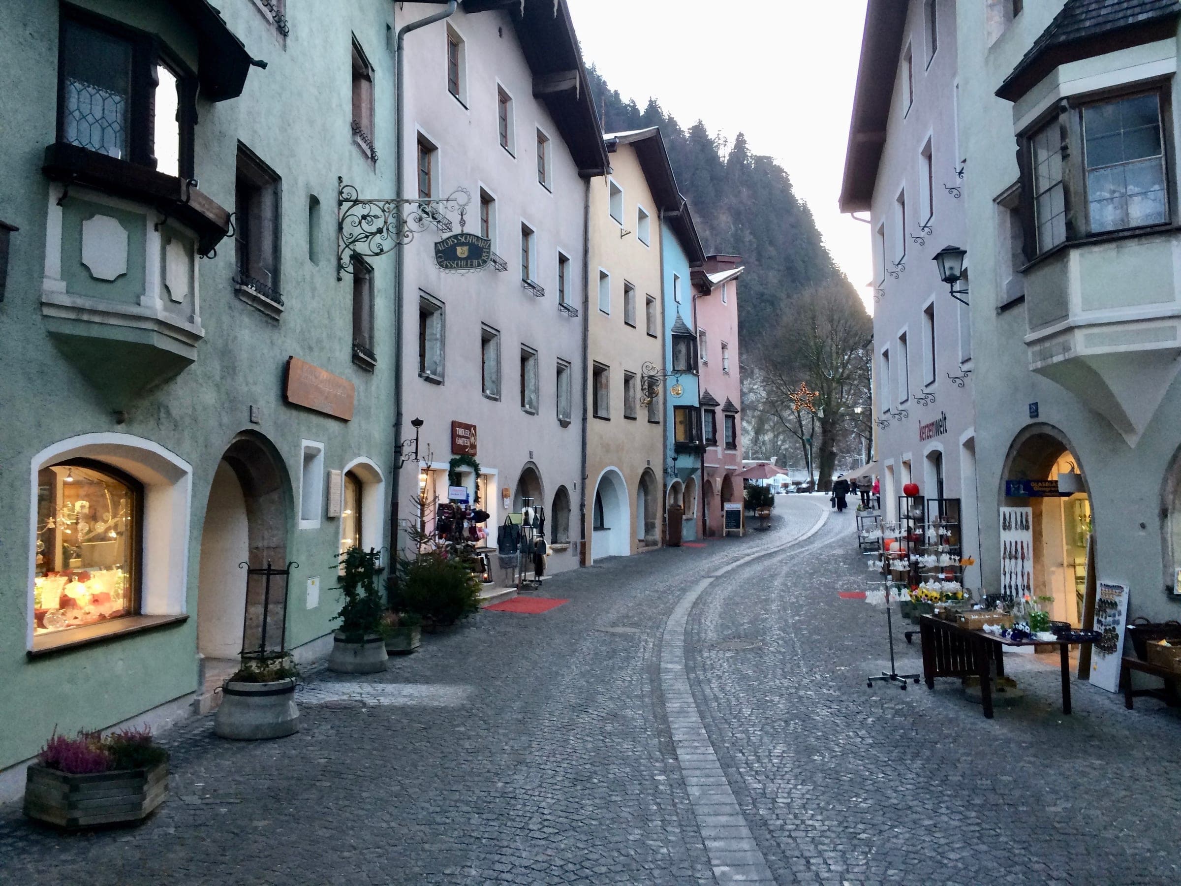 Shop windows glow along the cobbled main street of Rattenberg's old town on a December afternoon.