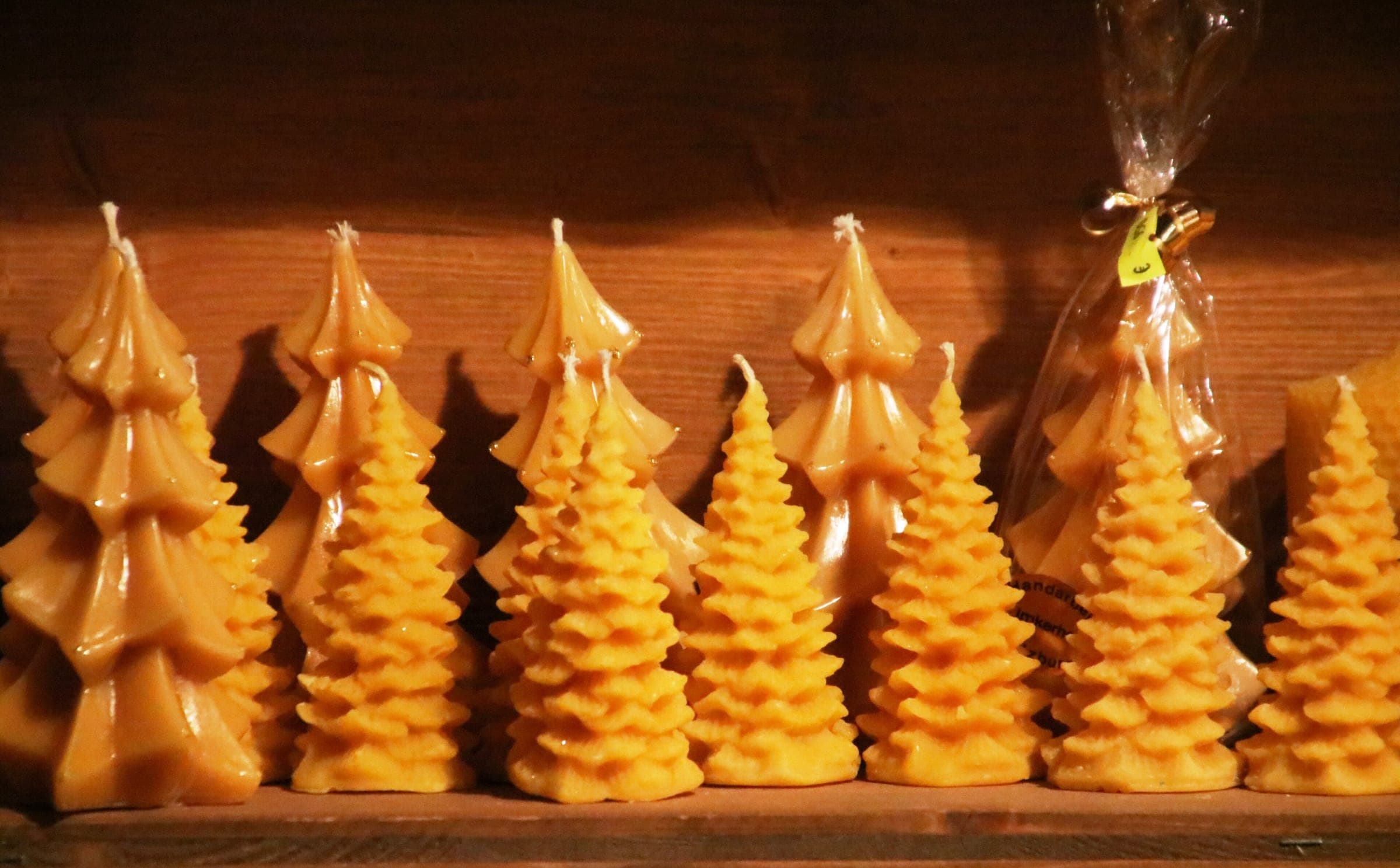 Beeswax candles shaped like fir trees stand in rows on a stall at the Hellbrunn Advent market