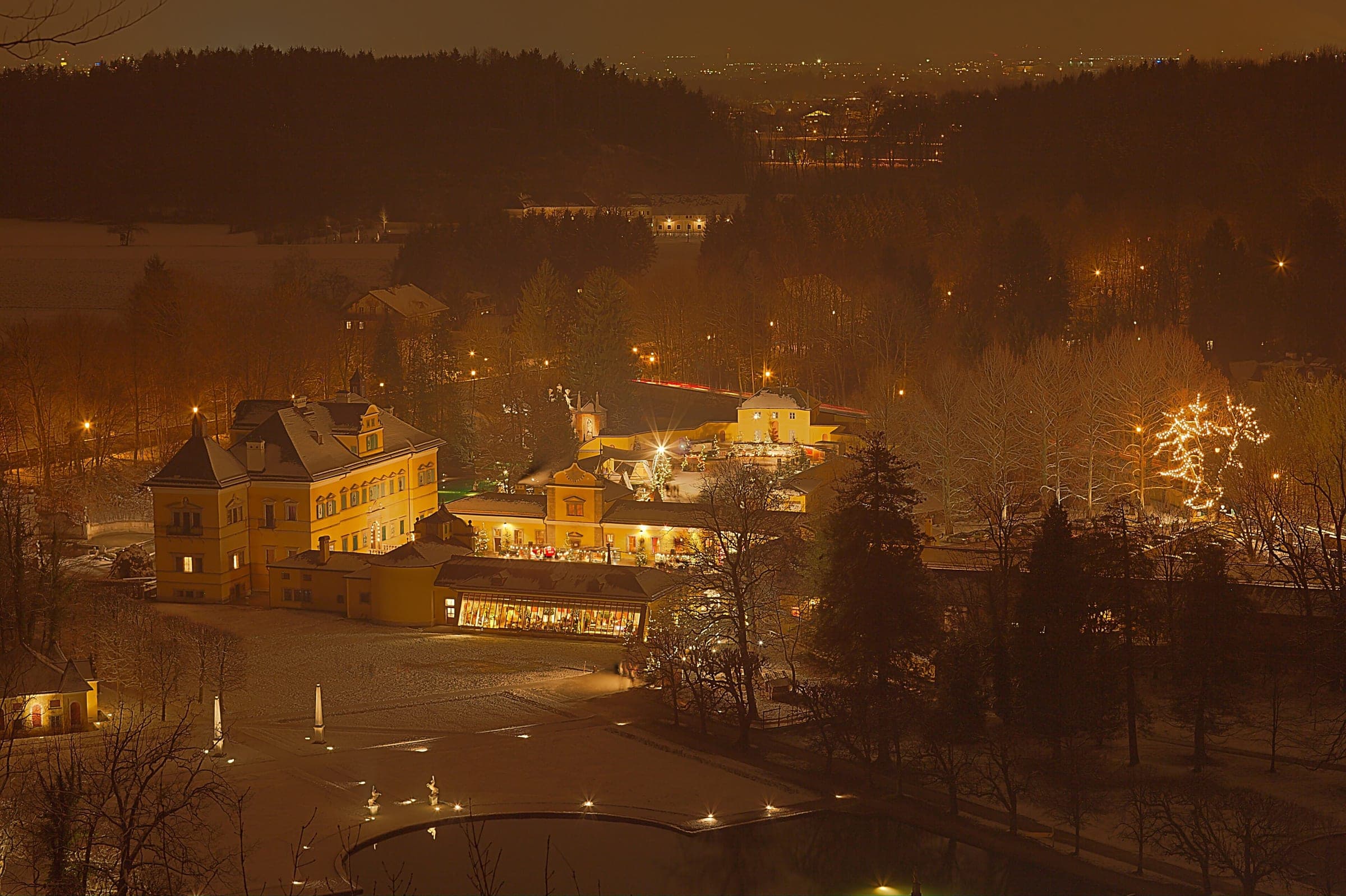 Snow lies over Schloss Hellbrunn and its park at night in a view from the Monatsschlössl hill