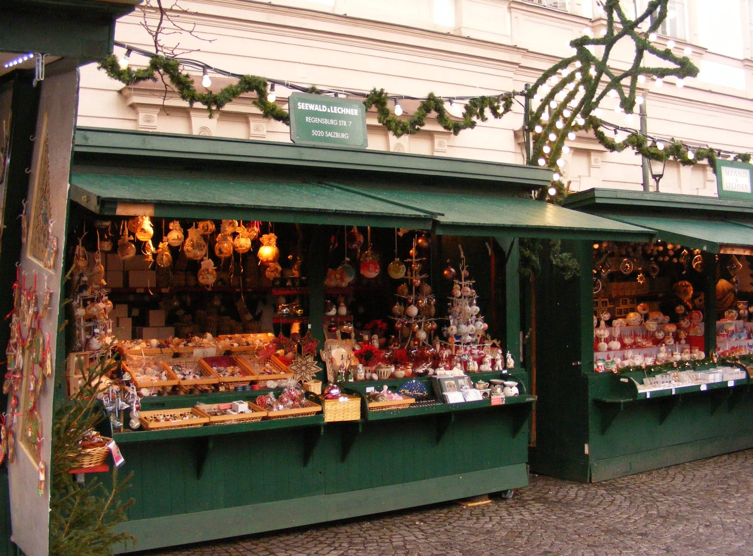 Glass baubles and straw stars fill a green wooden stall at the Mirabellplatz Christmas market in Salzburg