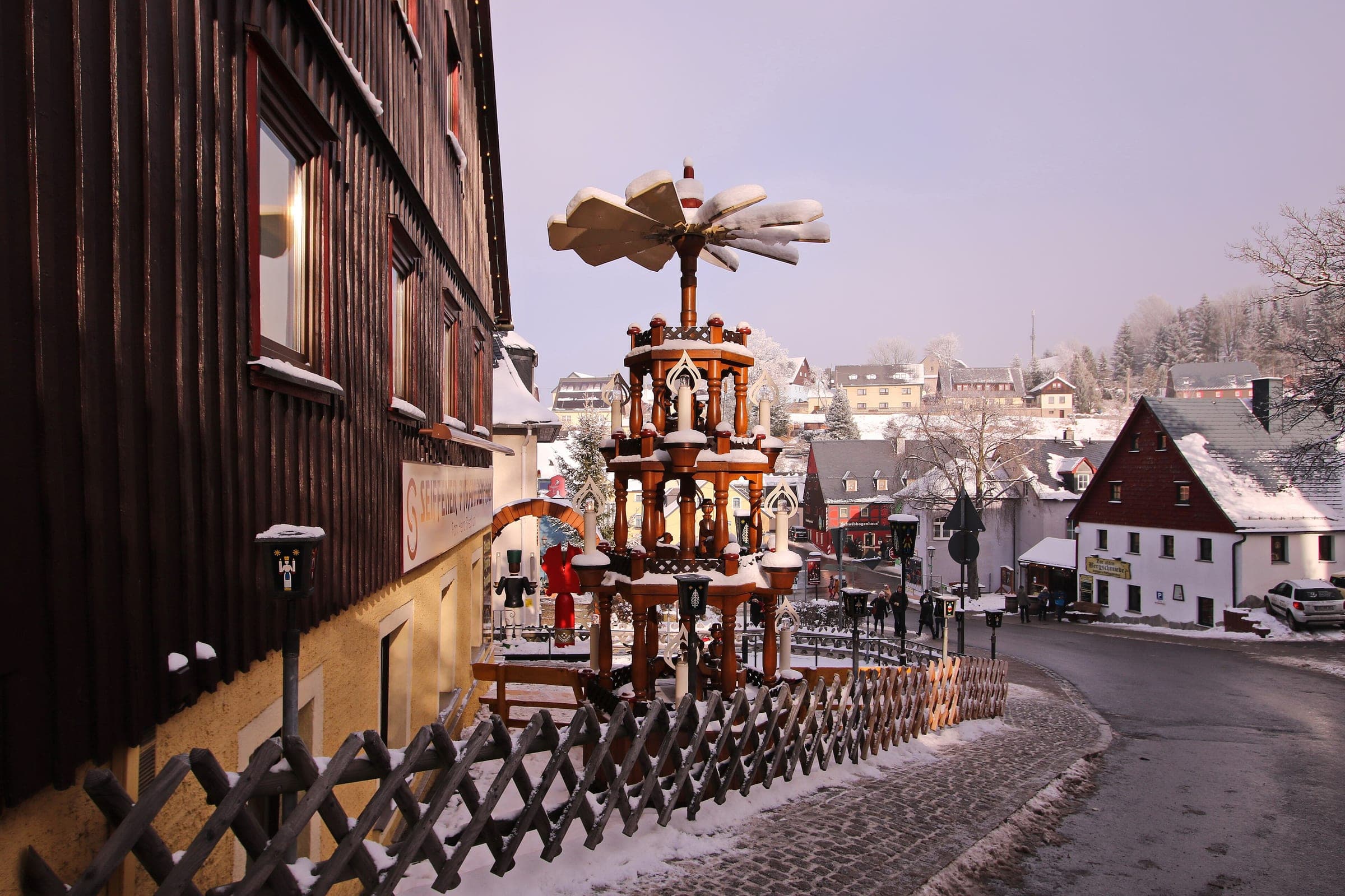 The tall village pyramid stands by the snowy main street of Seiffen as dusk settles.