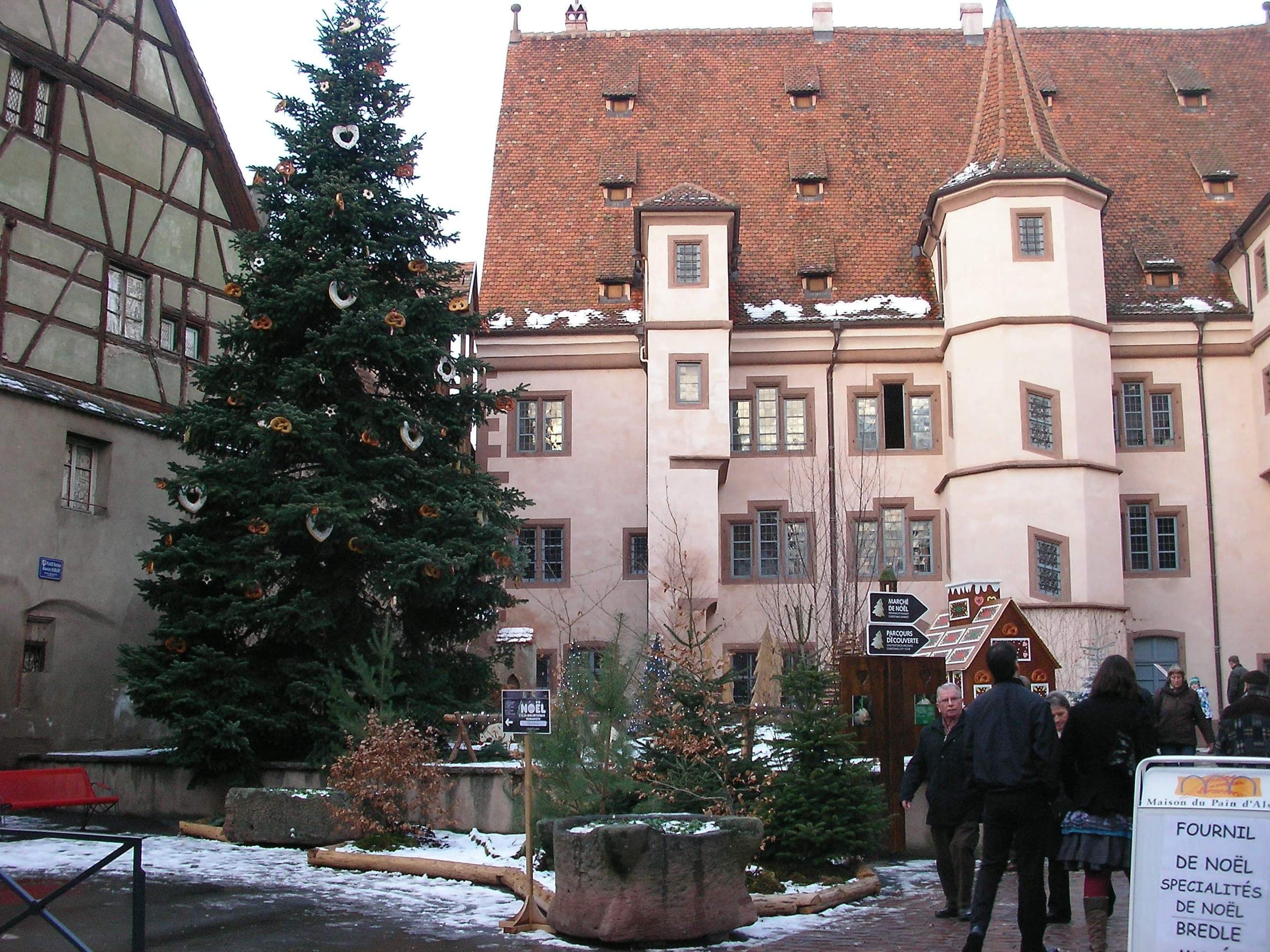 A decorated fir stands in the snow on rue du Sel in Sélestat in front of the Hôtel d'Ebersmunster.