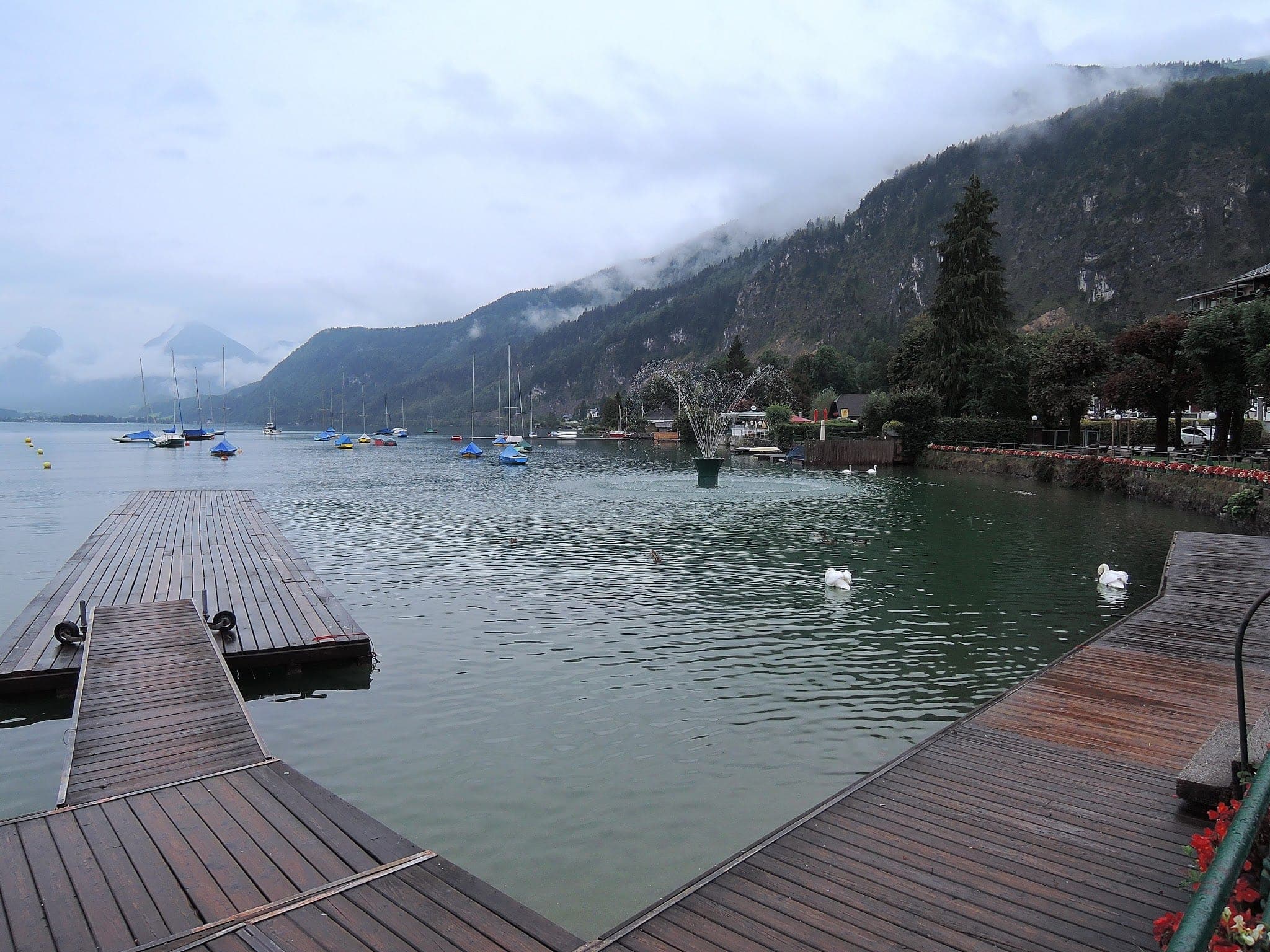 Wooden jetties reach into the Wolfgangsee from the lakeshore promenade in St Gilgen