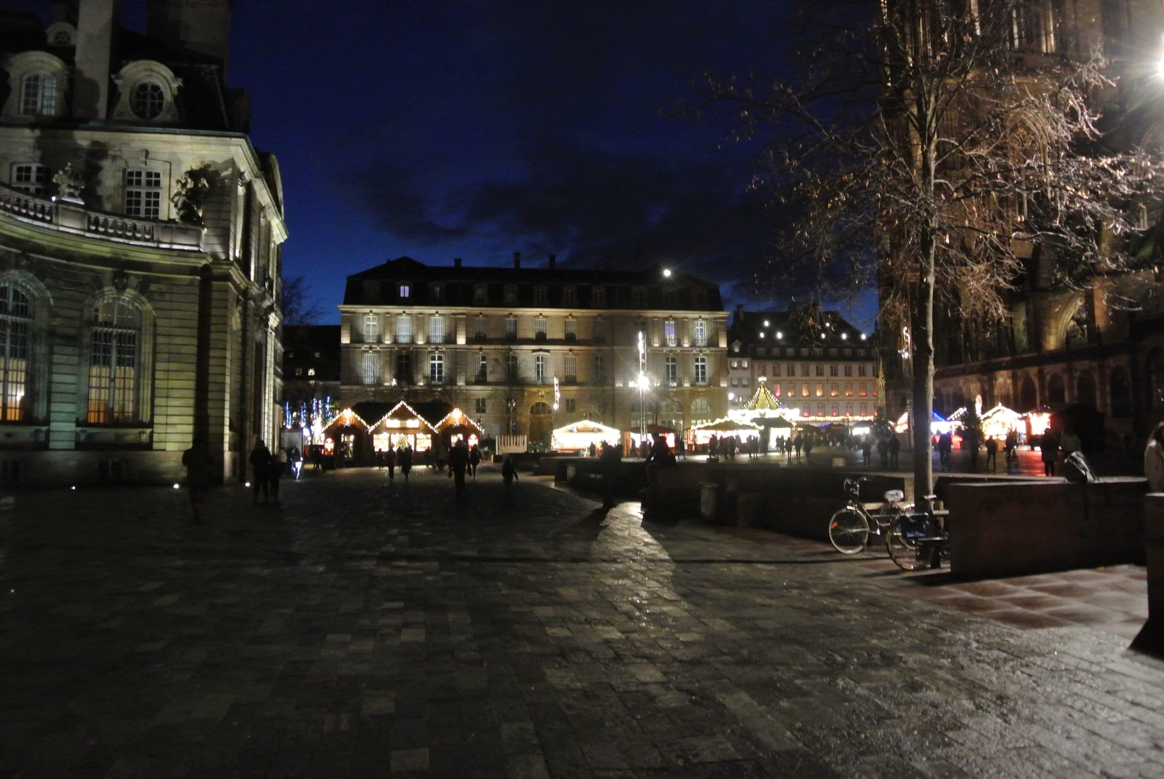 Lit chalets line Place du Château in Strasbourg in front of the Palais Rohan on a December night.