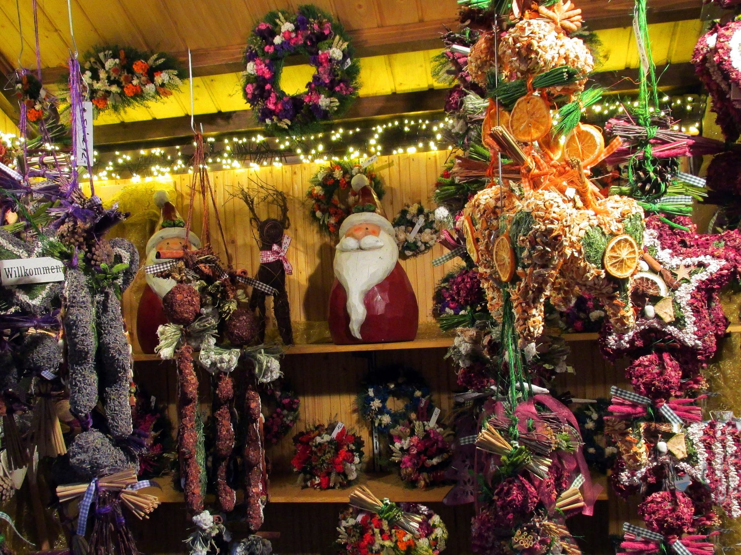 A stall at the Stuttgart Christmas Market hangs wreaths, dried flowers and Father Christmas figures under its lights.