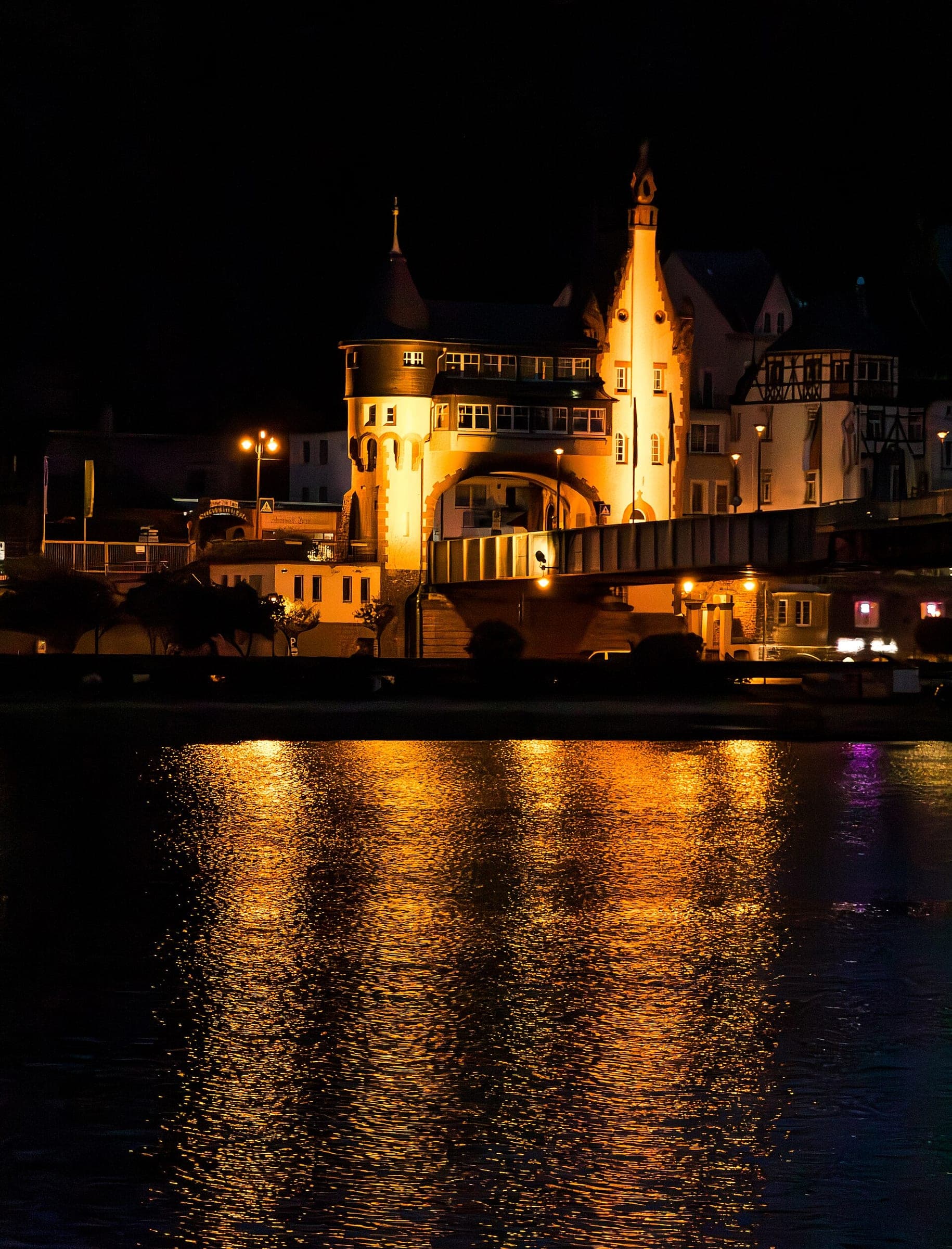 The Art Nouveau bridge gate of Trarbach glows over the dark Moselle at night