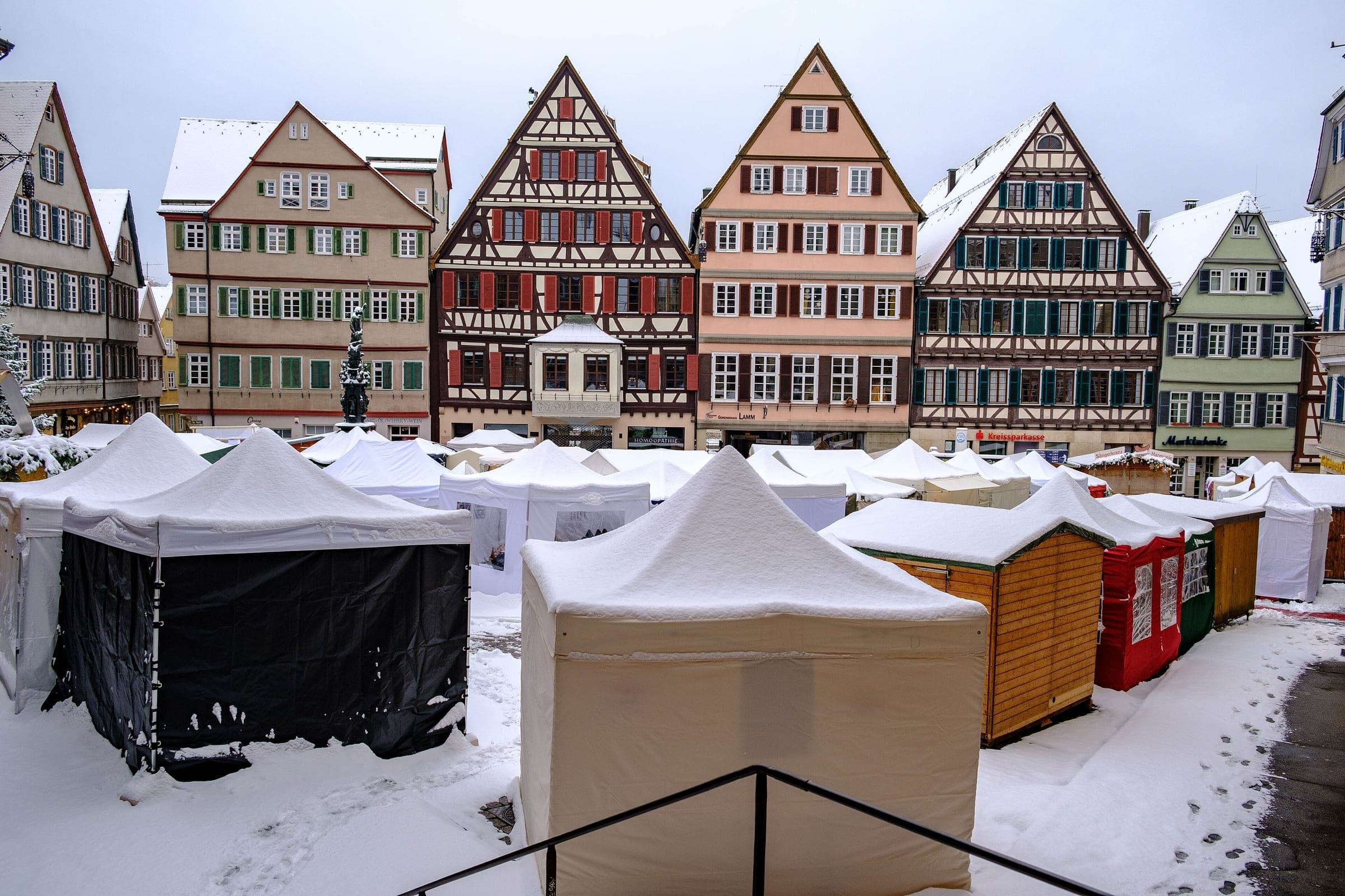 Snow covers the market stalls on Tübingen's Marktplatz in front of a row of timber-framed gables.