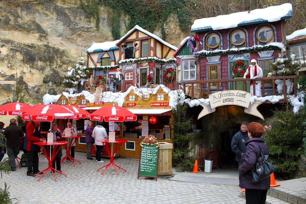 Snow-capped house fronts frame the cave entrance of the Fluweelengrot Christmas market in Valkenburg.