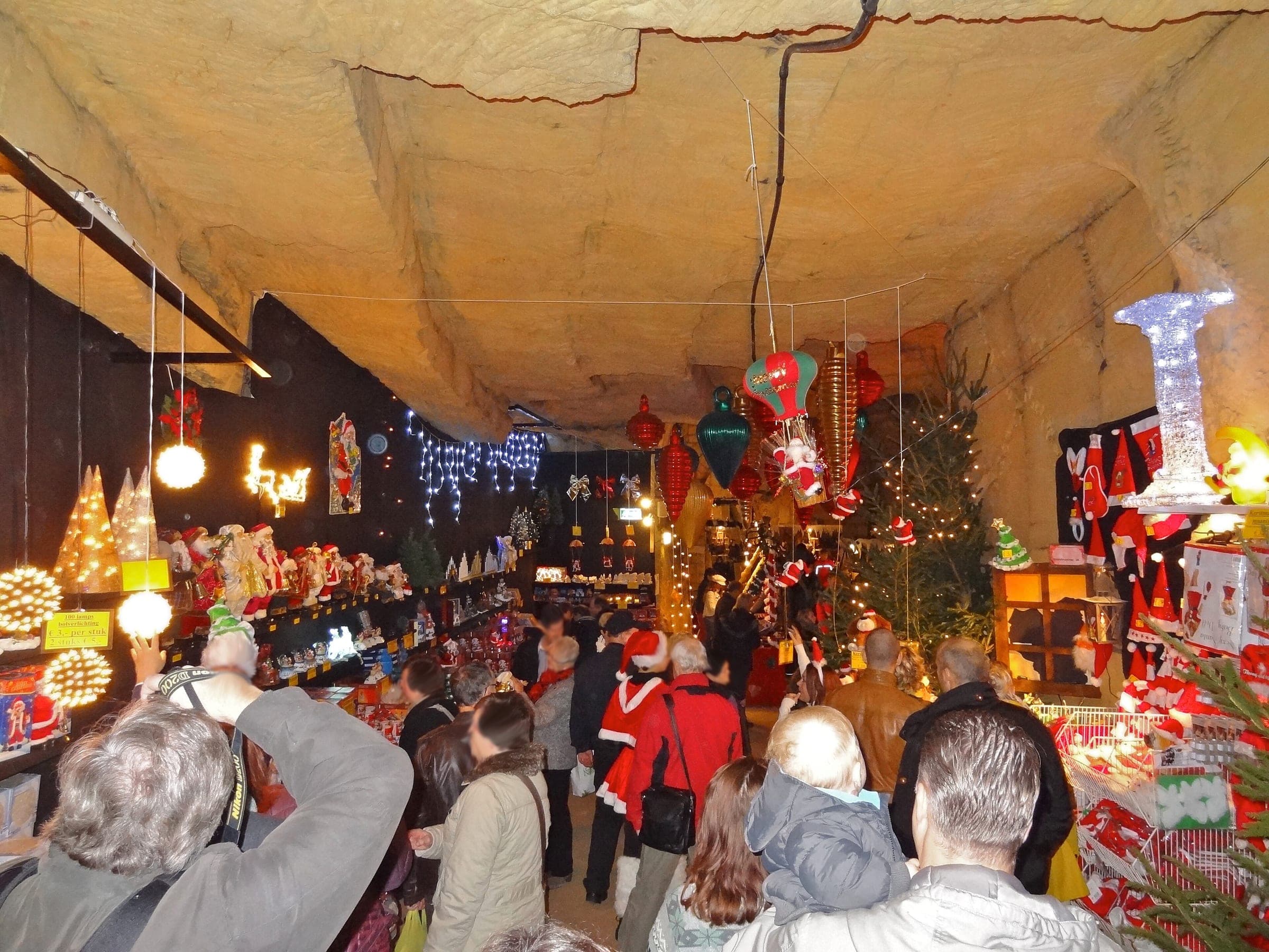 Visitors squeeze past decorated stalls in the low marl passages of the Fluweelengrot Christmas market in Valkenburg.