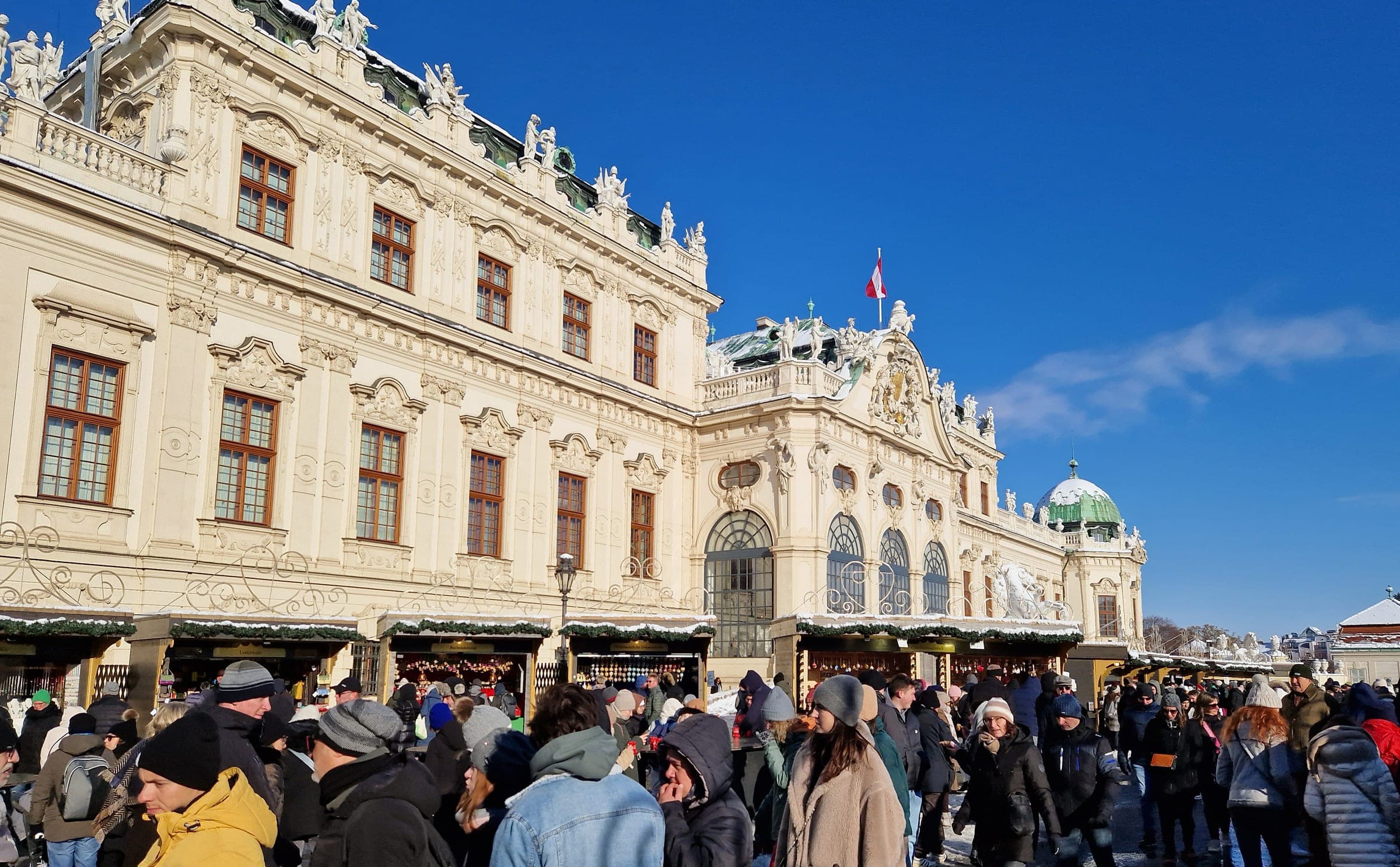 Crowds browse the Christmas stalls in front of the Upper Belvedere palace in Vienna on a clear December day.