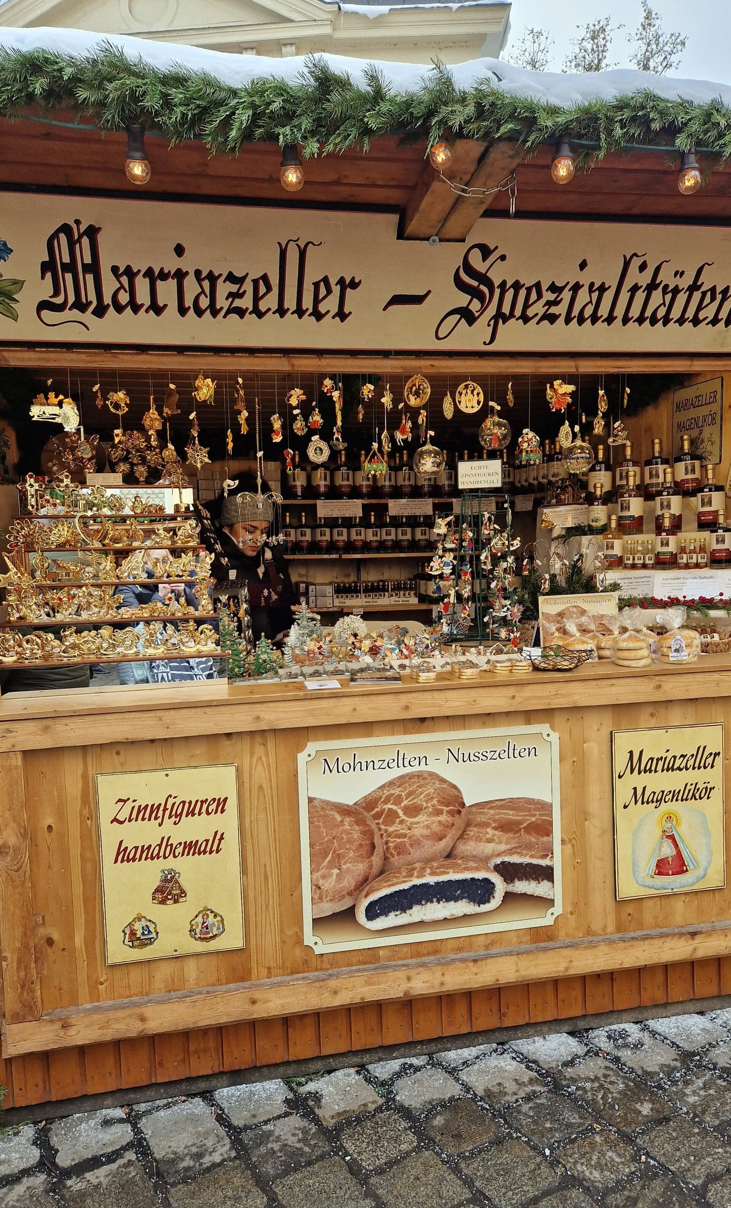 A Mariazell stall on the Freyung in Vienna sells painted tin figures and poppy seed cakes under a snowy roof.