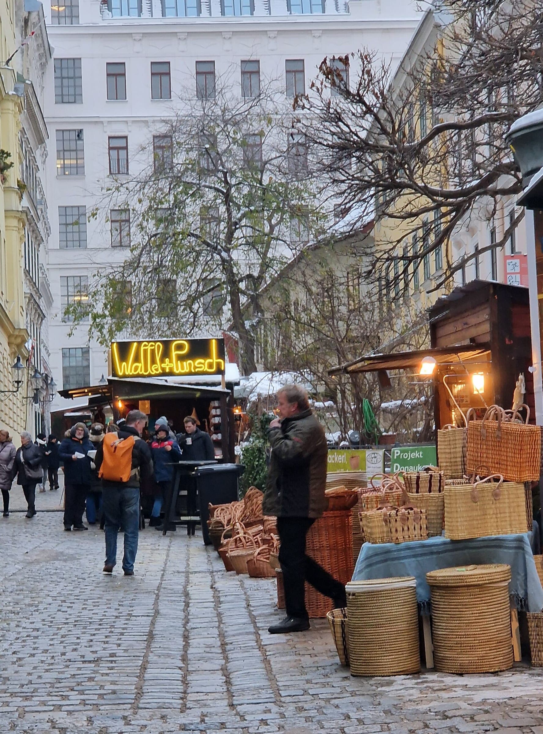 Woven baskets sit outside a stall as visitors queue for waffles and punch at the Spittelberg market in Vienna.