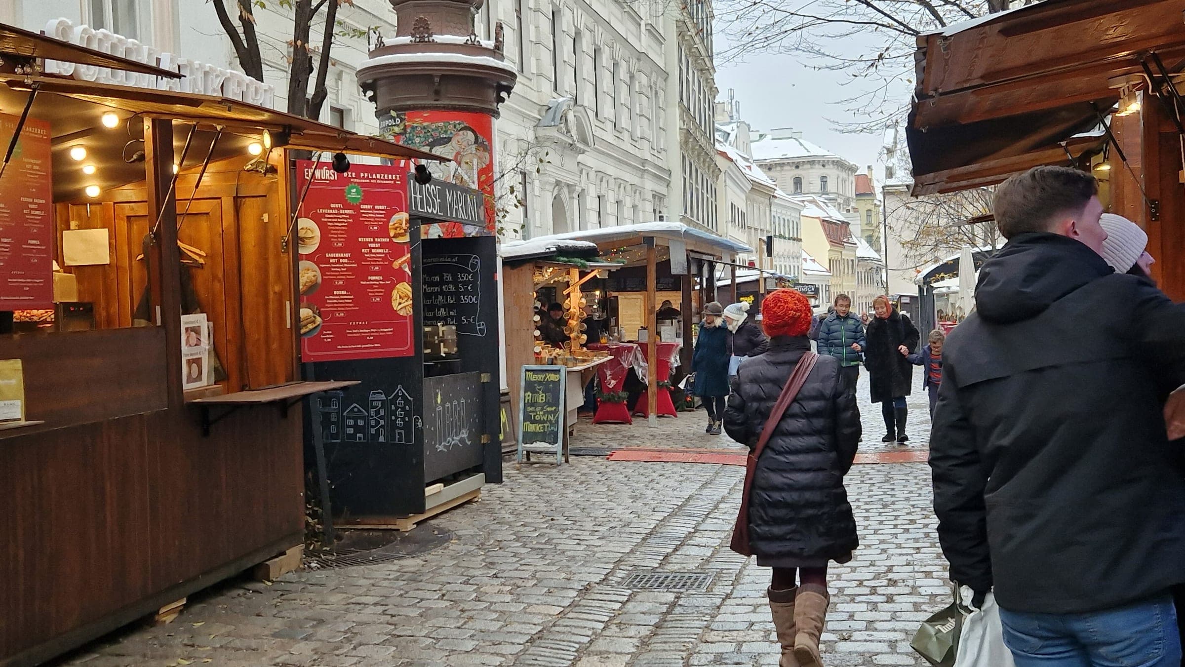 Shoppers walk a cobbled lane lined with wooden stalls at the Spittelberg Christmas market in Vienna.