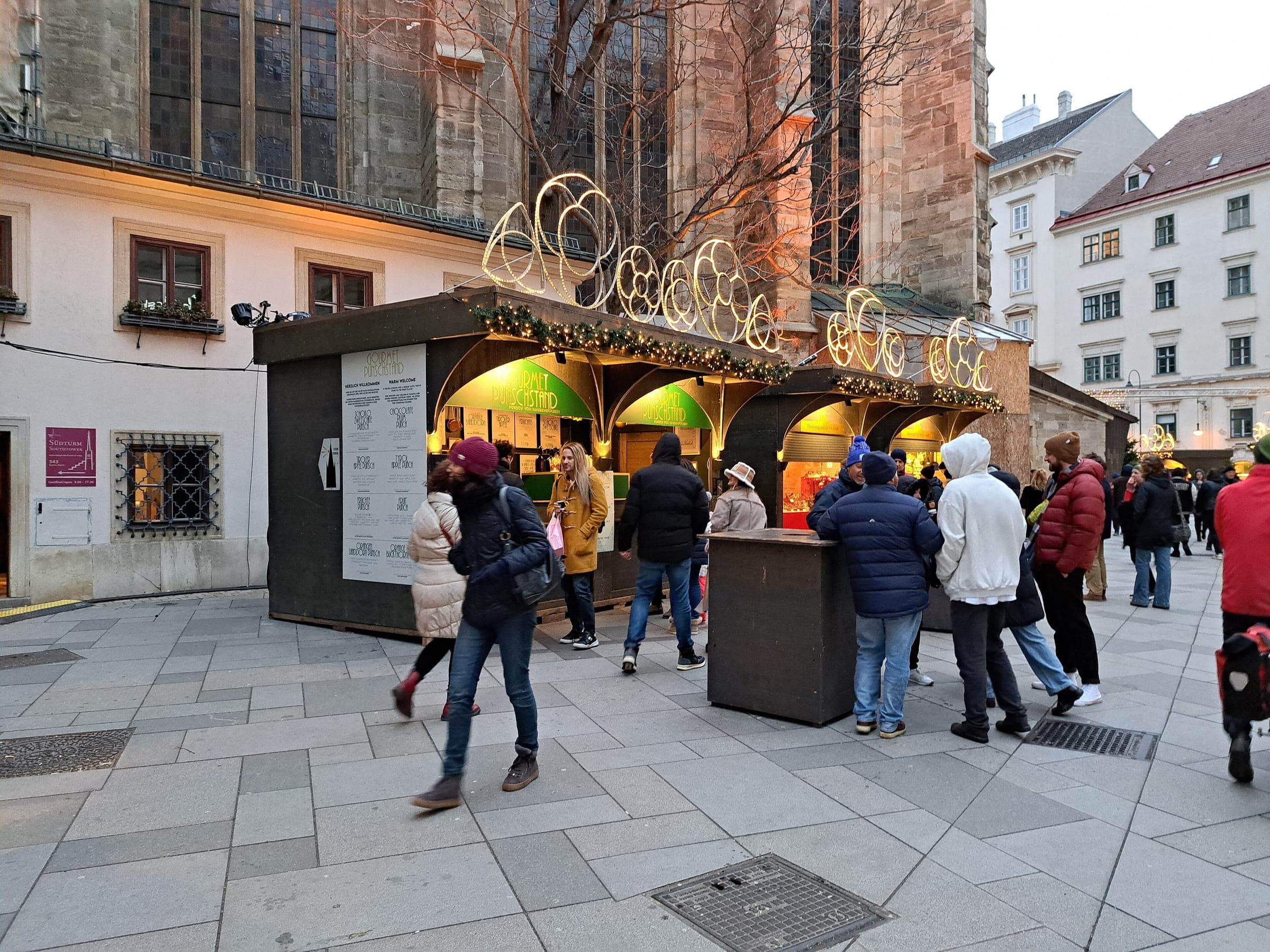 Shoppers gather at lit wooden stalls of the Stephansplatz market in Vienna at the foot of the cathedral.