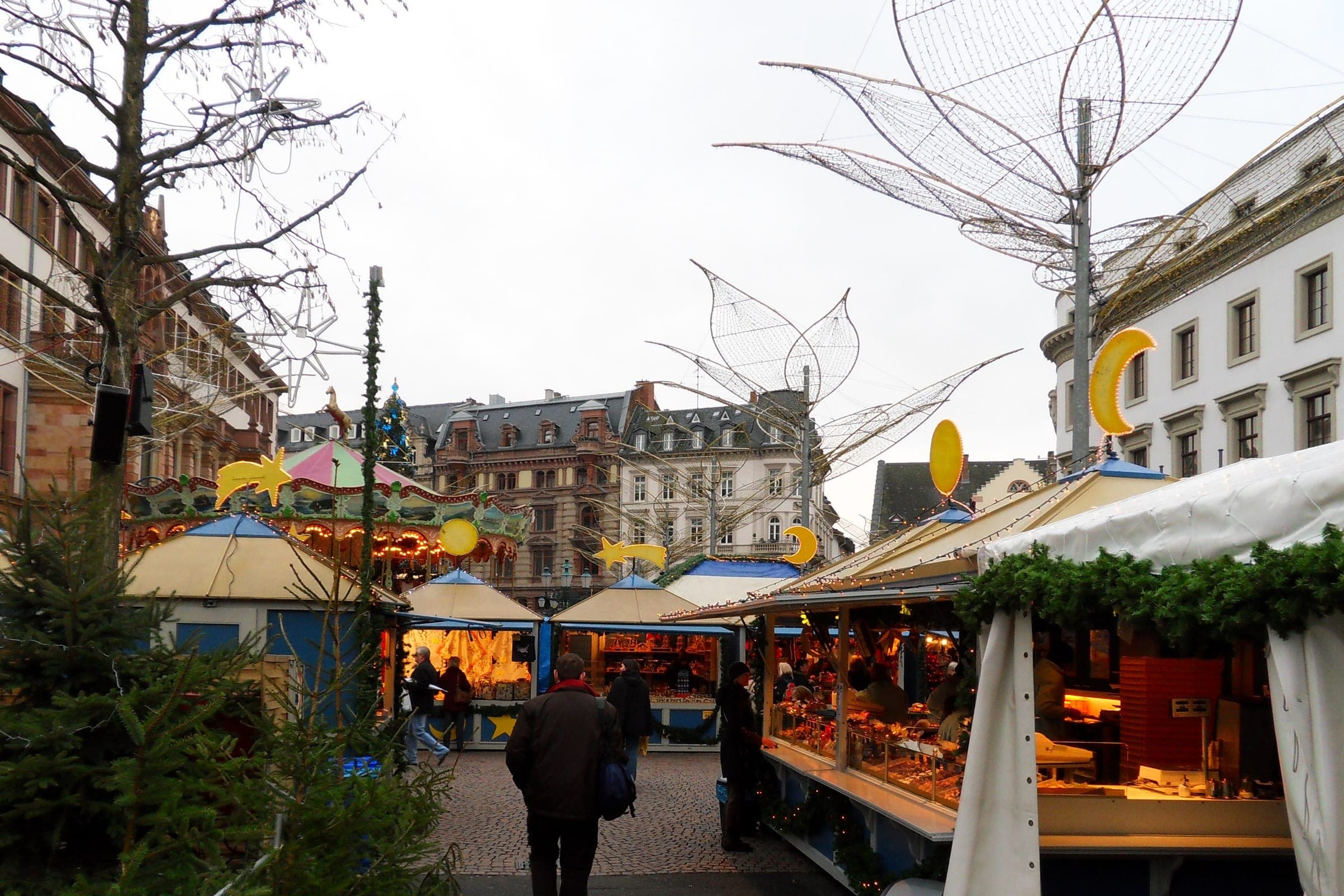 Stalls with blue roofs and yellow moons line the lanes of the Sternschnuppenmarkt in Wiesbaden on a grey day.