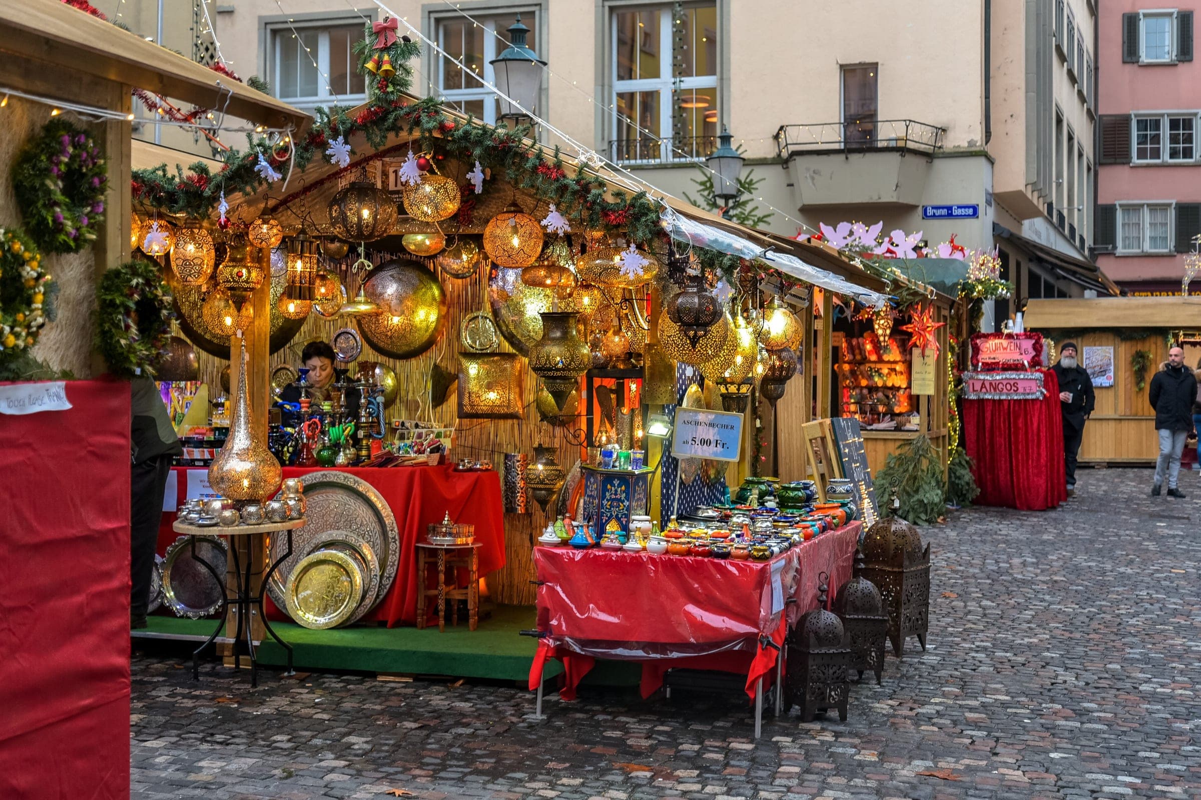 Brass lanterns and painted bowls crowd a garlanded stall on Hirschenplatz in Zurich's Niederdorf
