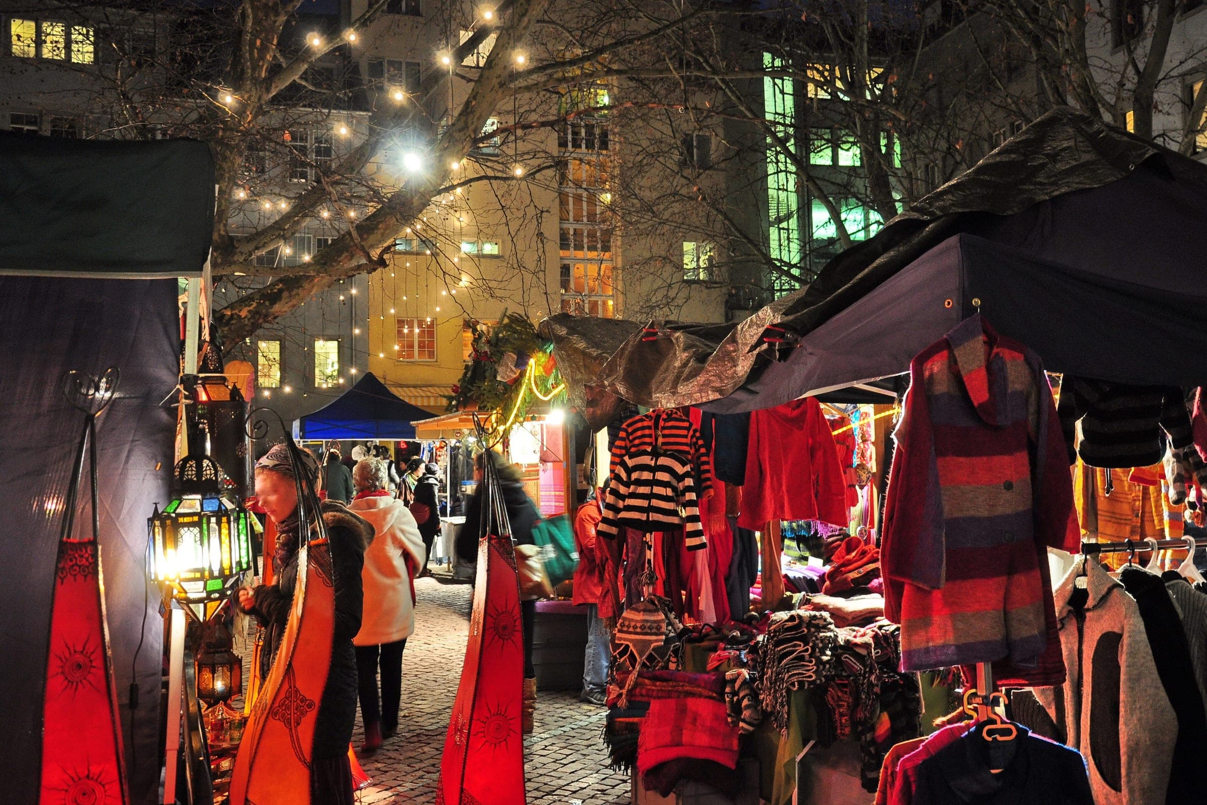 Lanterns and knitwear hang from stalls on a cobbled lane of the Niederdorf Christmas market in Zurich