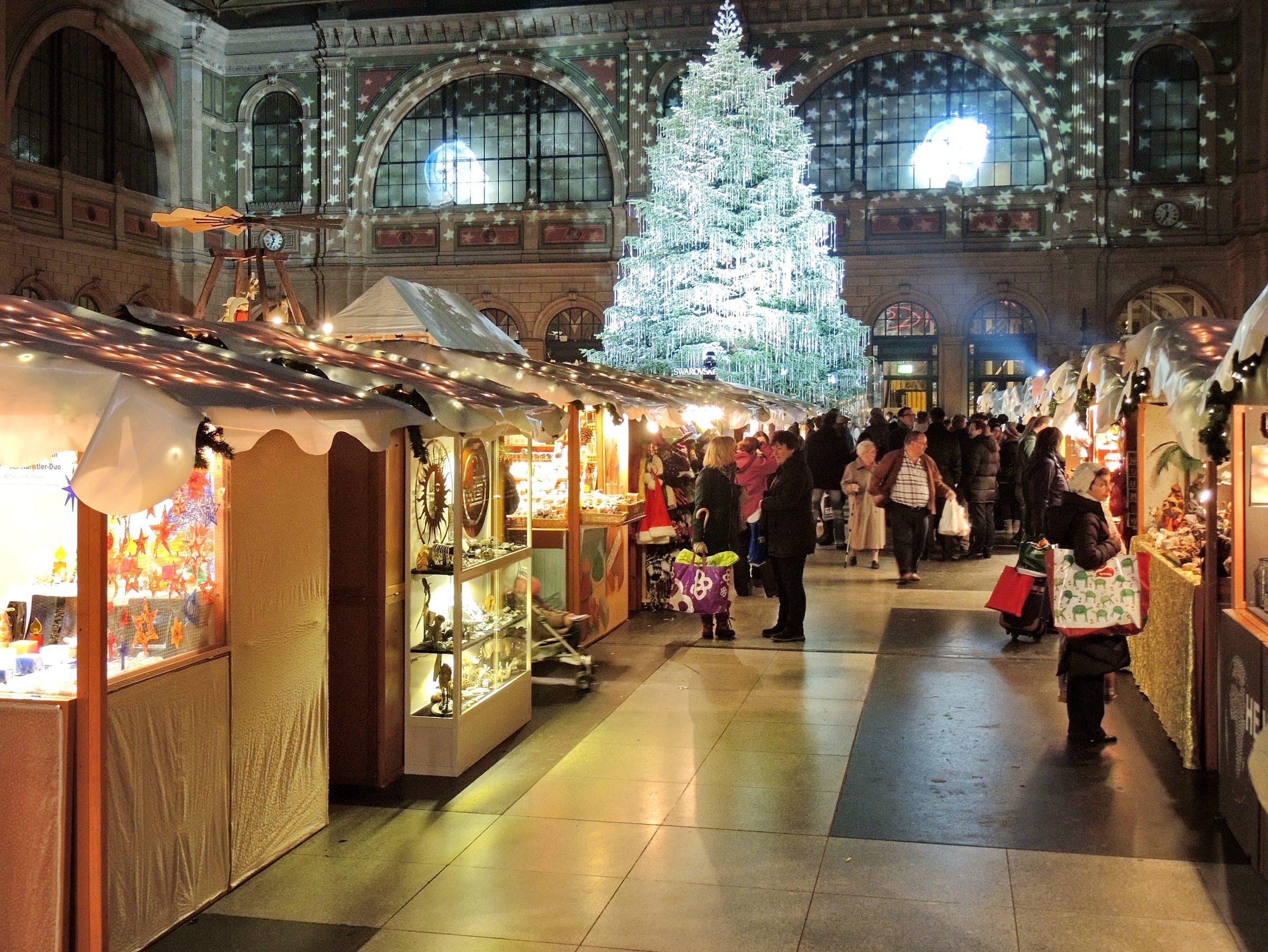 Christmas stalls fill the hall of Zurich main station beneath a tall tree hung with crystals