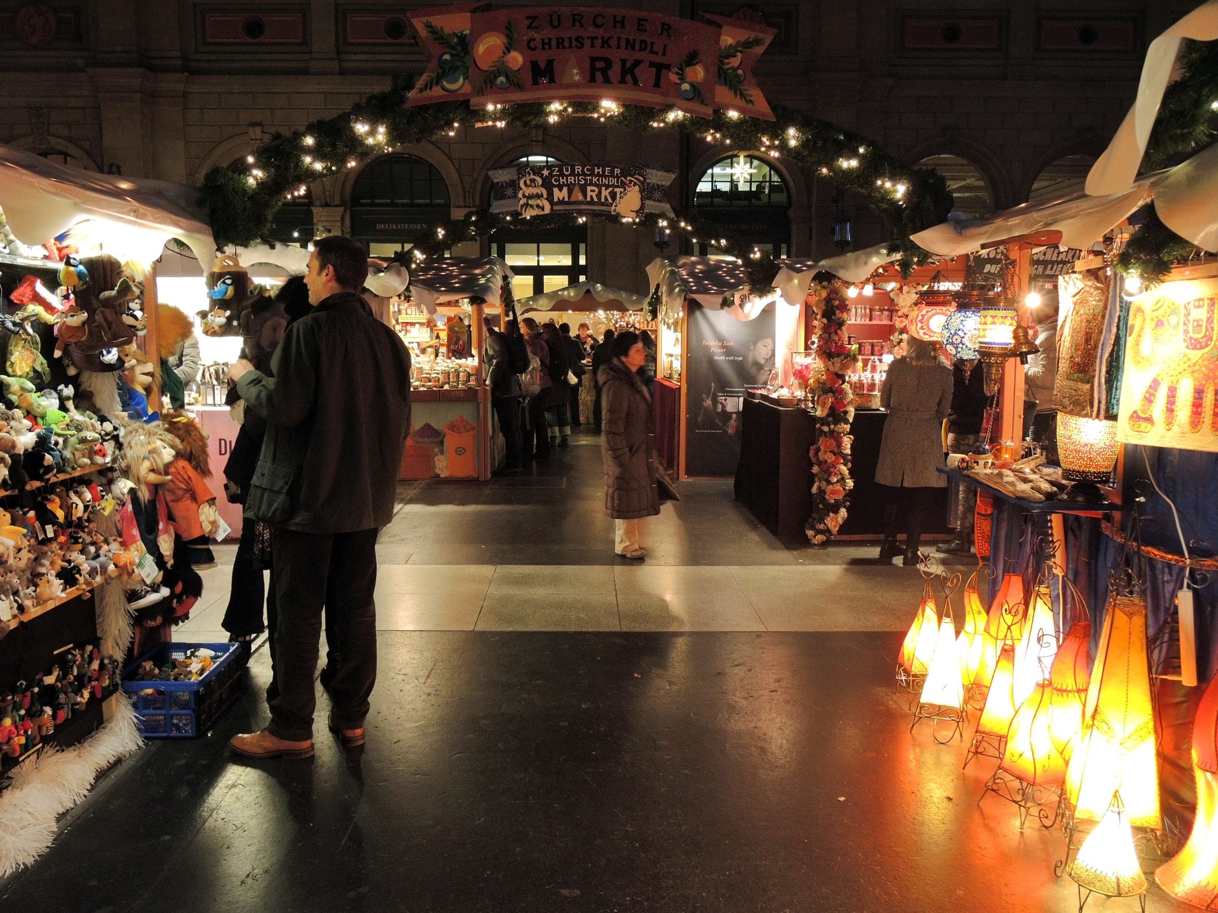 Paper lanterns glow along a lane of stalls at the Christmas market inside Zurich main station