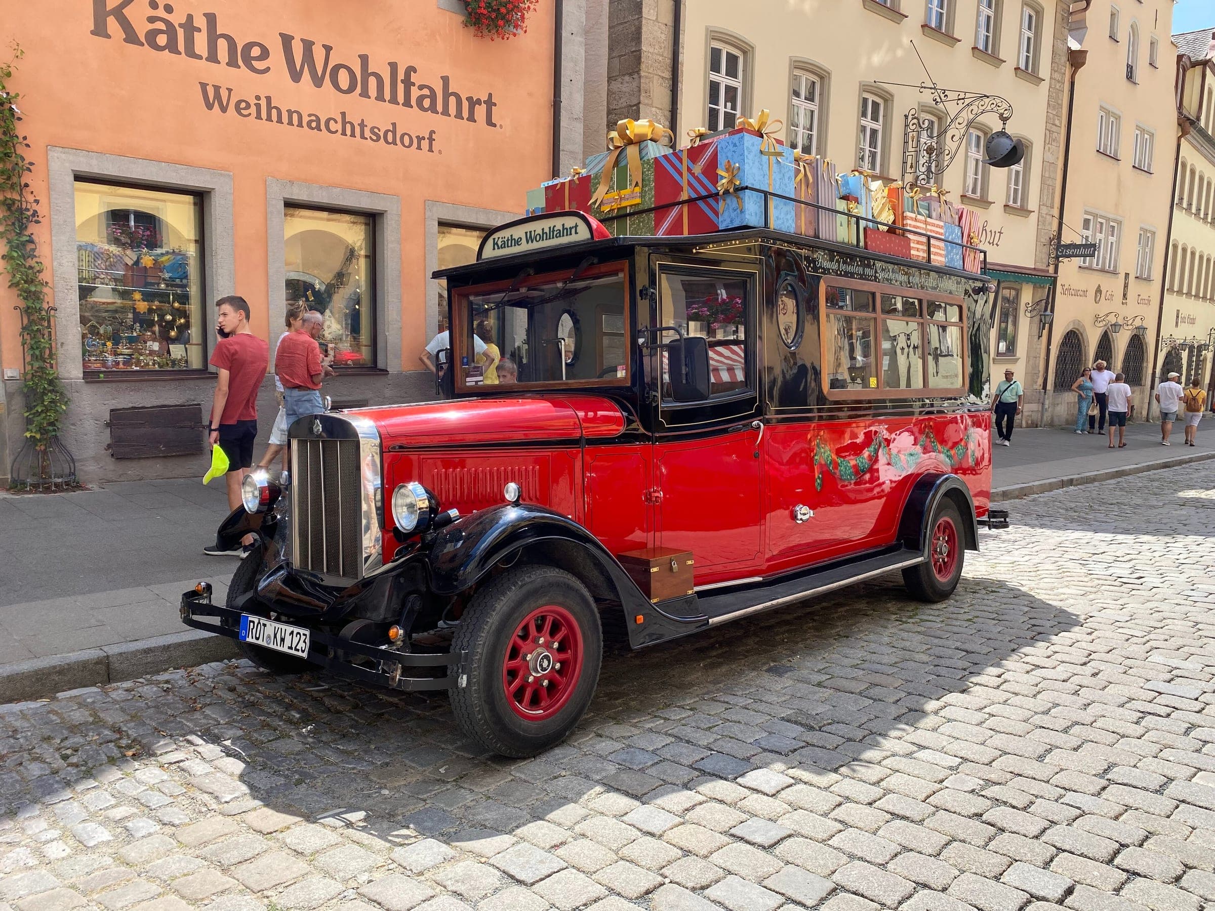 A red vintage bus stacked with parcels stands outside Käthe Wohlfahrt's Christmas Village on Herrngasse in Rothenburg.
