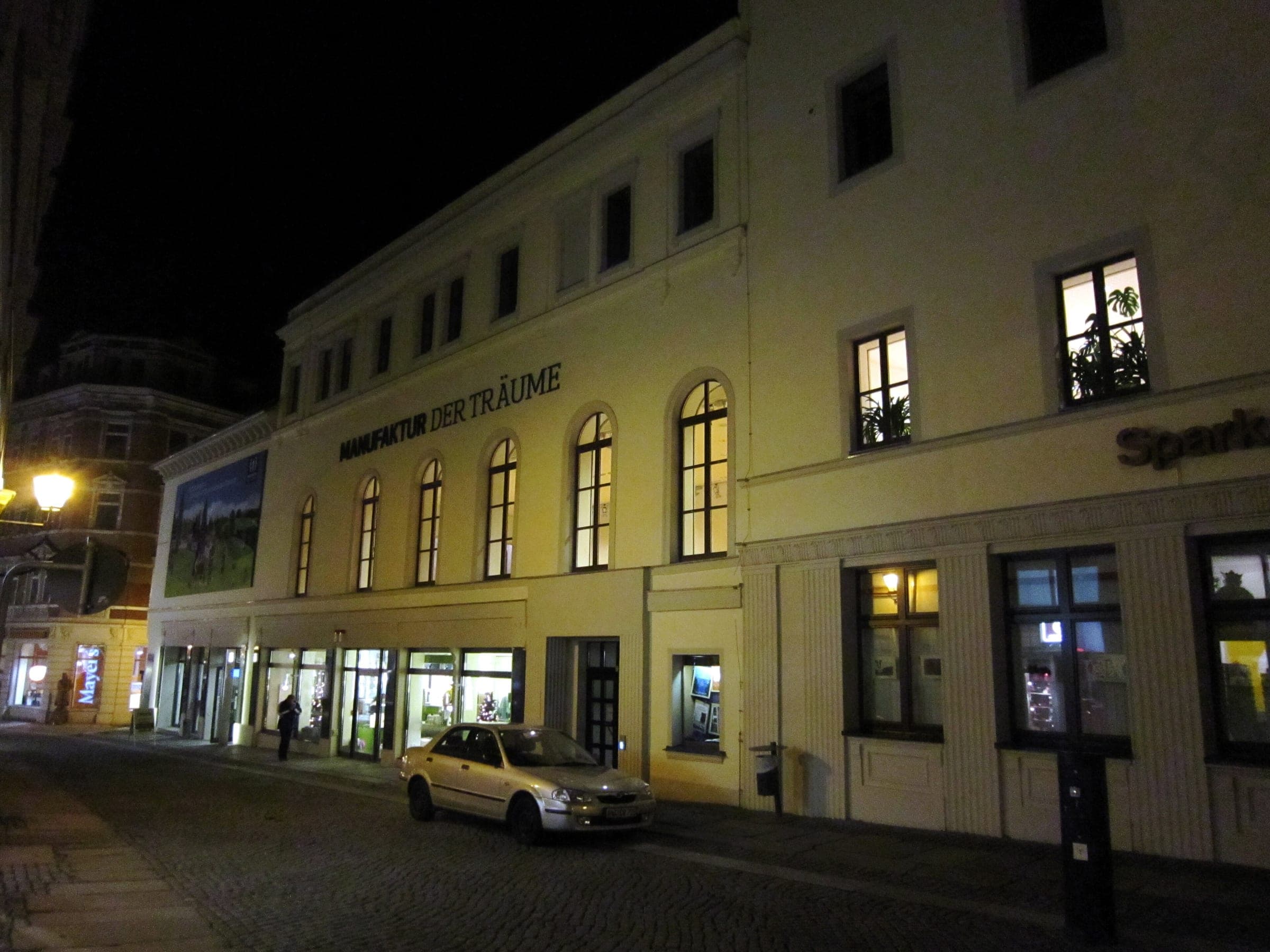 Lit windows line the front of the Manufaktur der Träume museum on Buchholzer Straße in Annaberg-Buchholz at night.