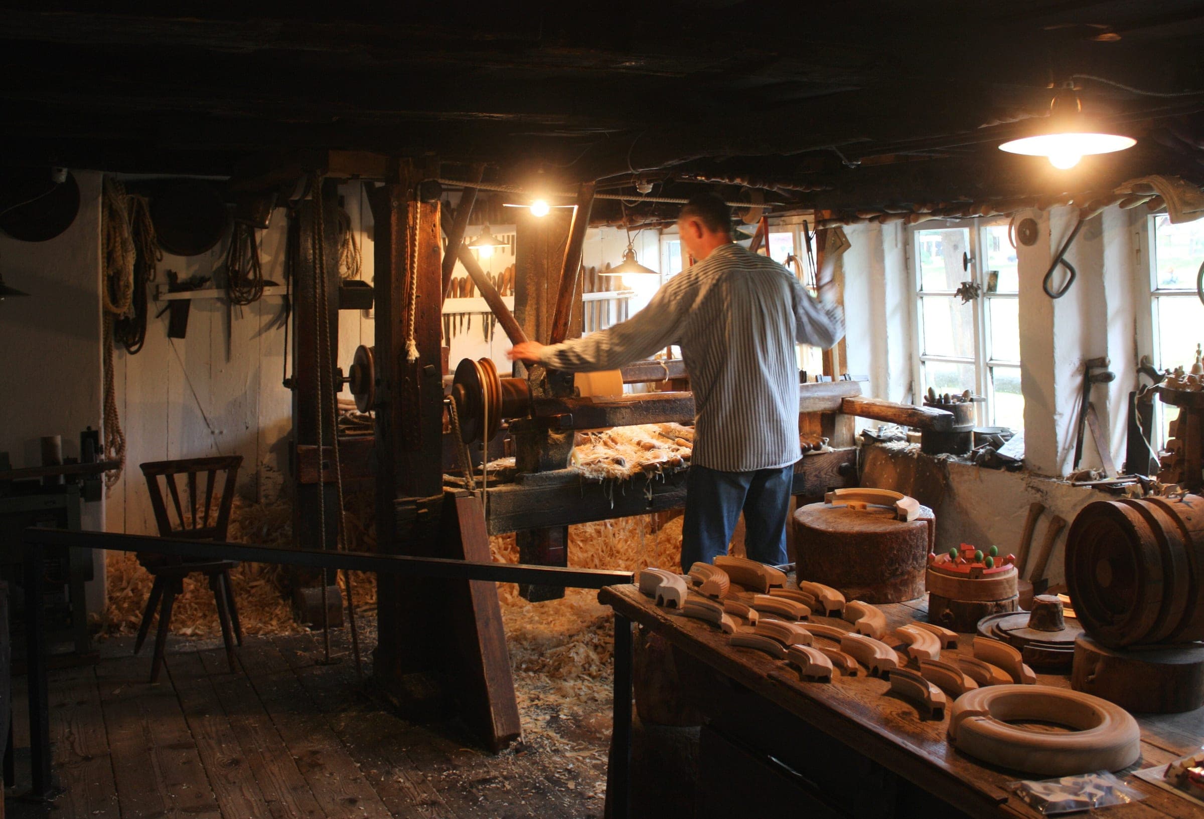 A turner shapes a wooden ring on the water-driven lathe at the Erzgebirge Open-Air Museum in Seiffen.