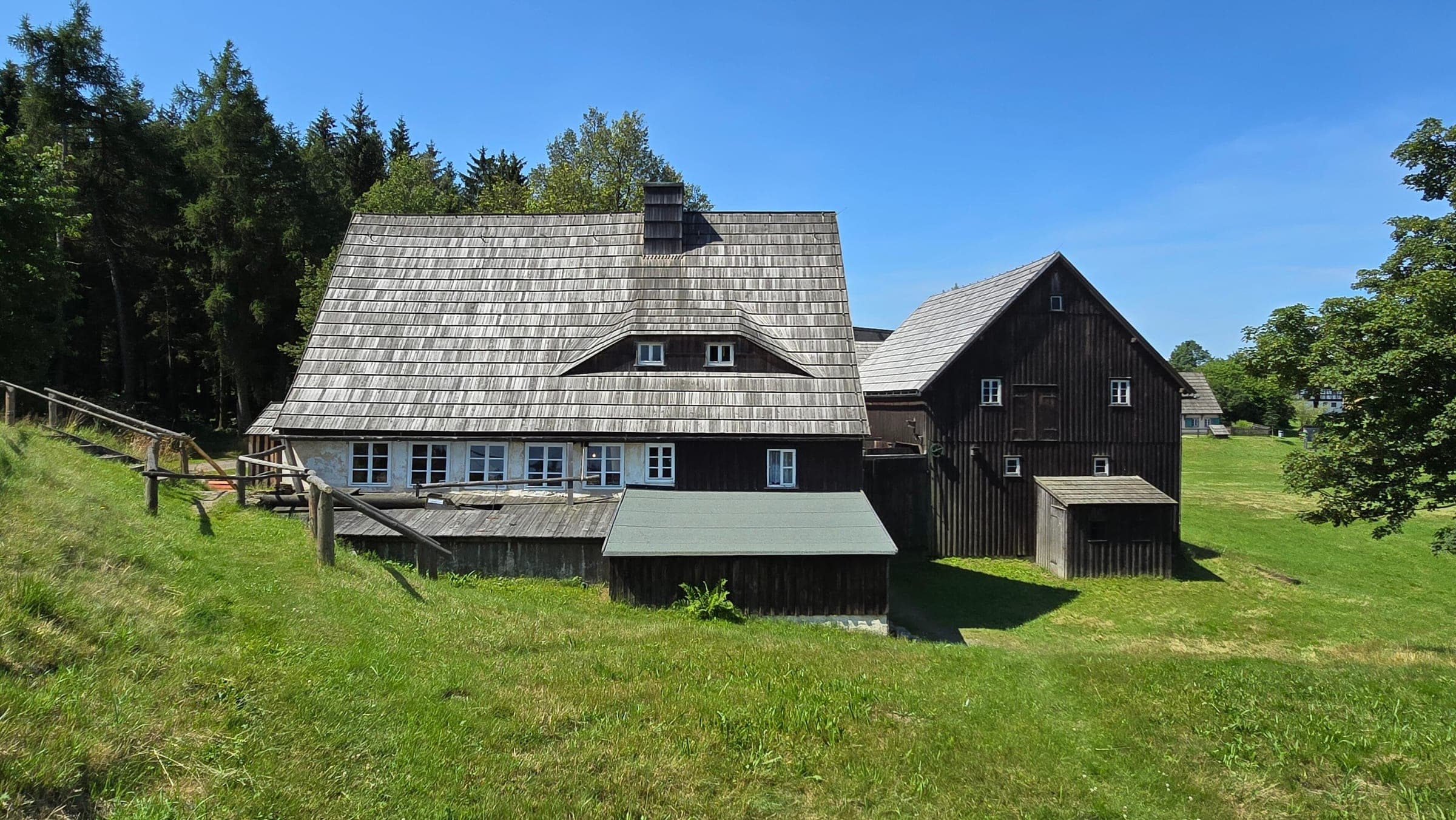 Shingled wooden houses of the water-powered turning mill stand on the grass of the Seiffen Open-Air Museum.