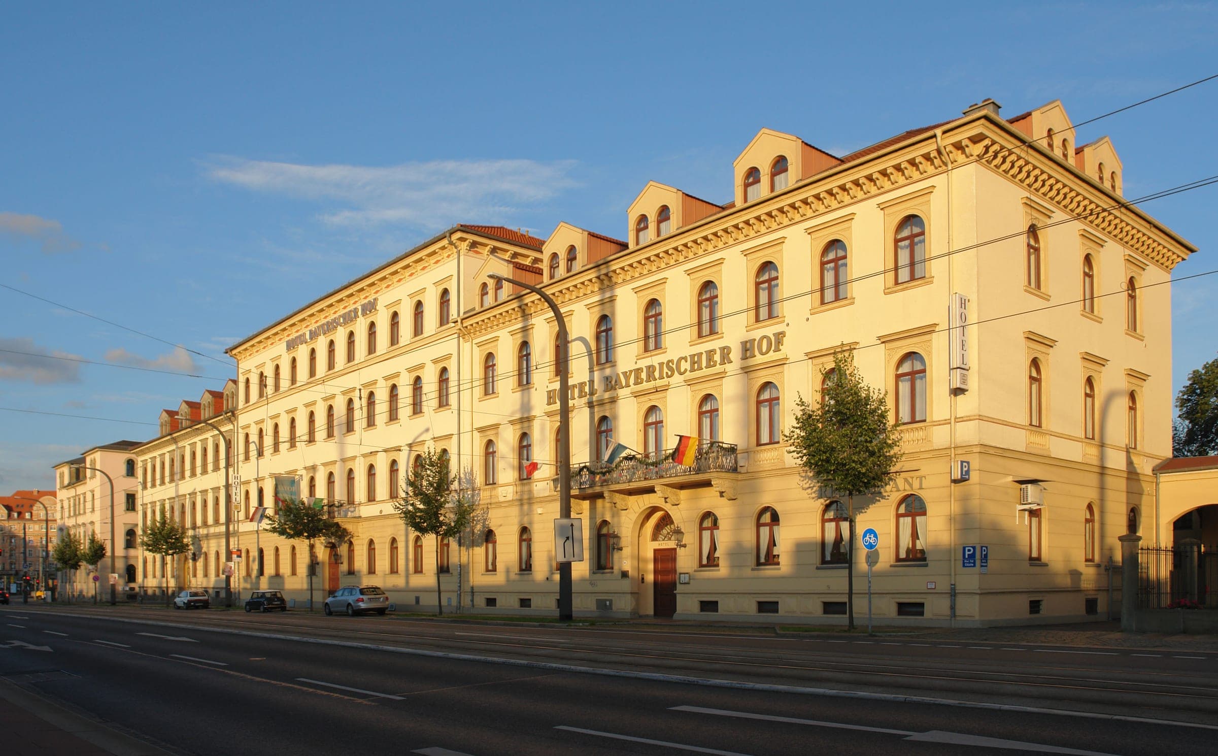 Evening sun warms the long yellow front of Hotel Bayerischer Hof on Antonstraße in Dresden's Neustadt.