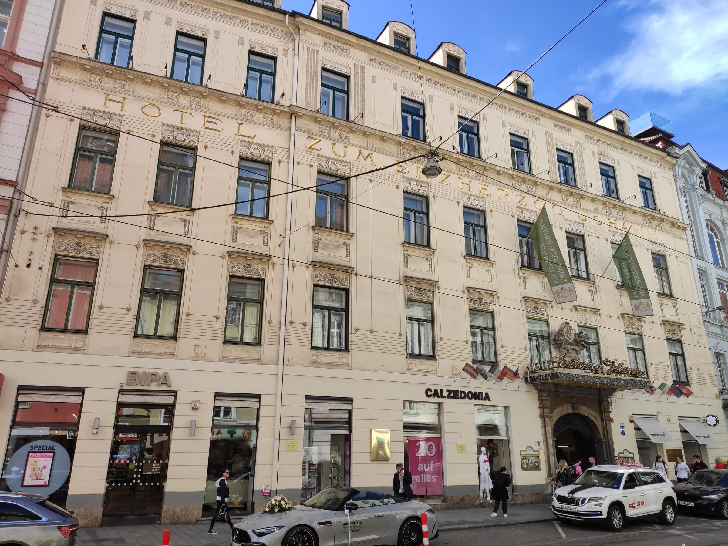 Gilt lettering and flags mark the pale façade of Palais-Hotel Erzherzog Johann on Sackstraße in Graz