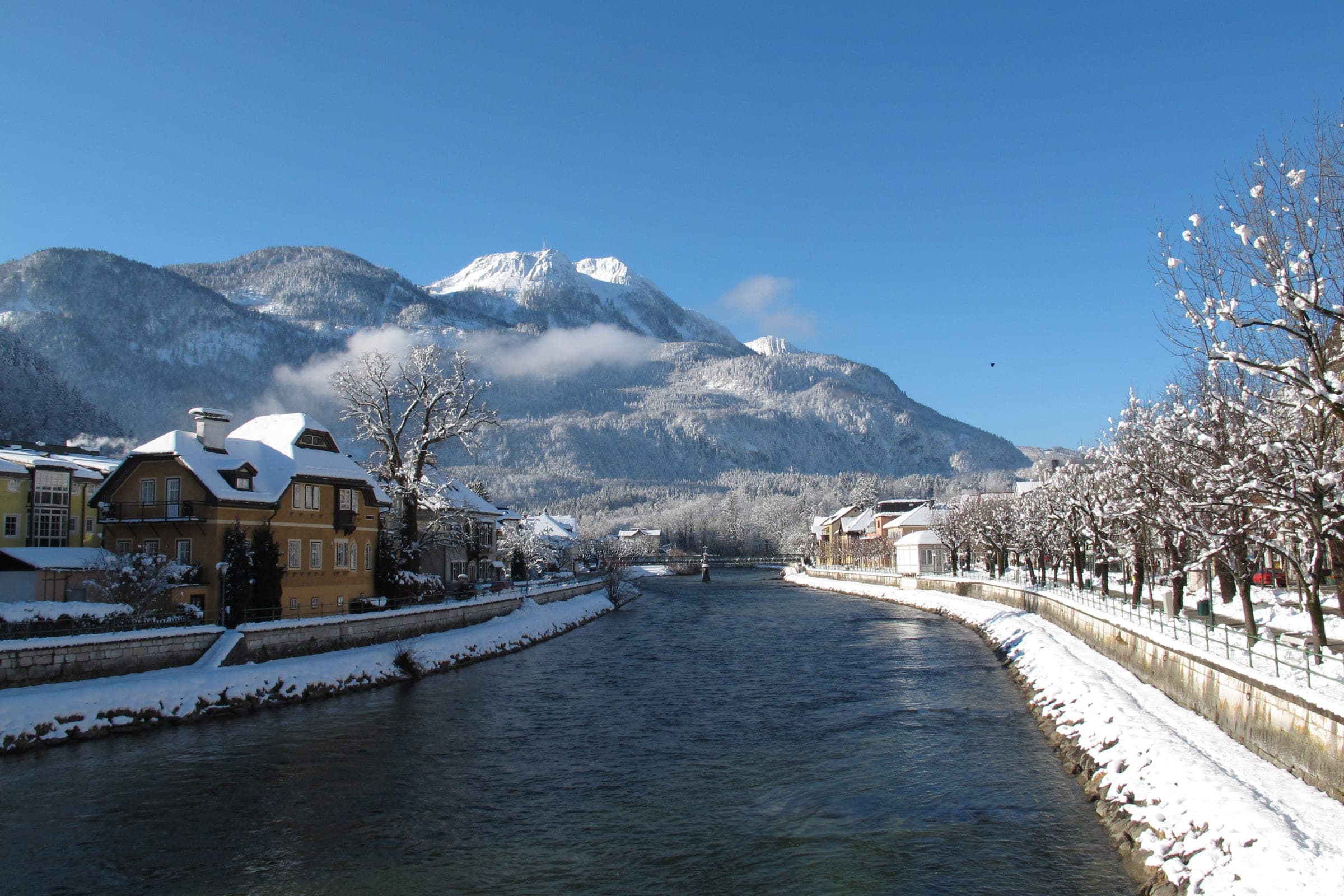 Snow lines both banks of the Traun as it flows through Bad Ischl below white mountains