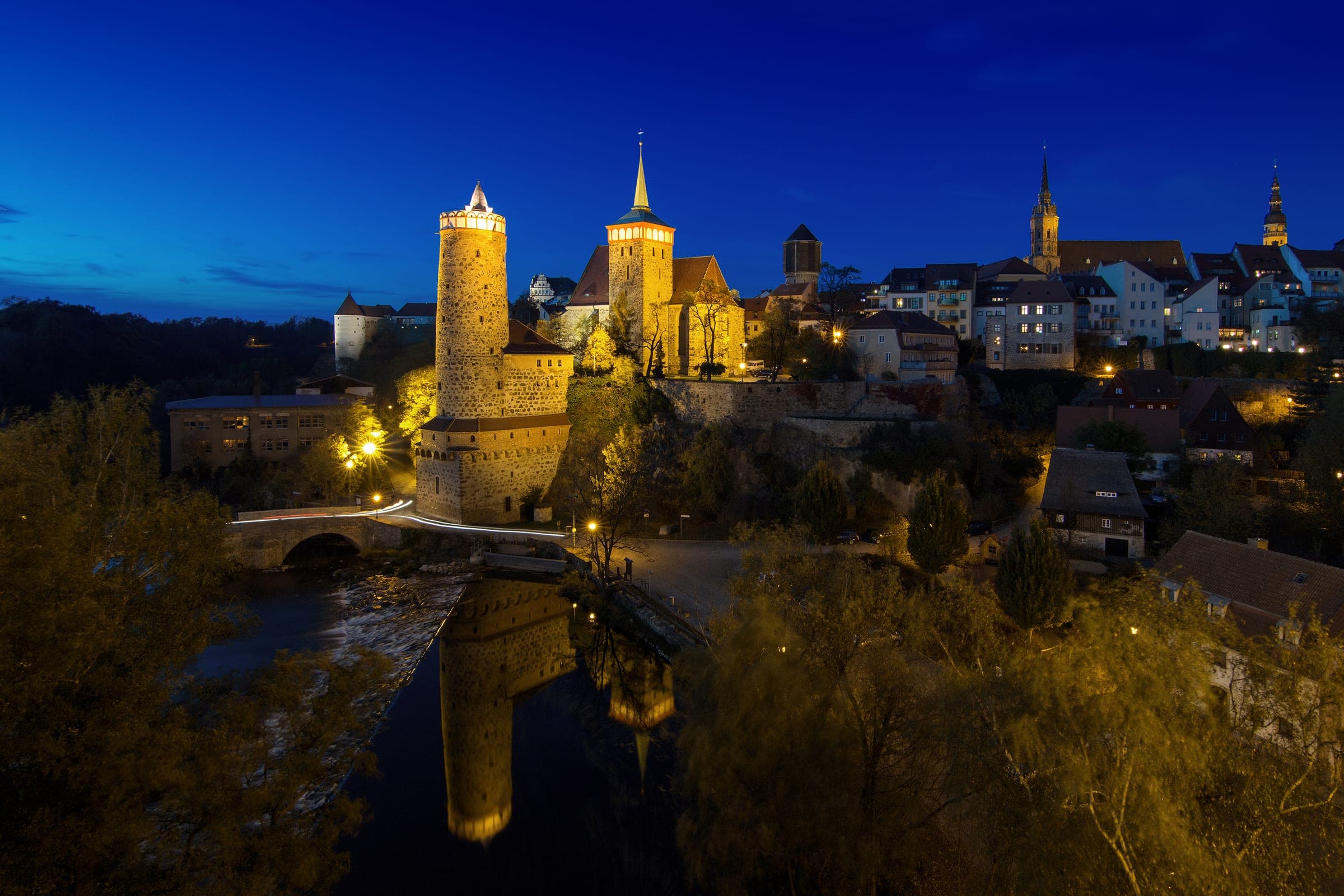 The Alte Wasserkunst tower and the Michaeliskirche glow above the Spree in Bautzen at blue hour.