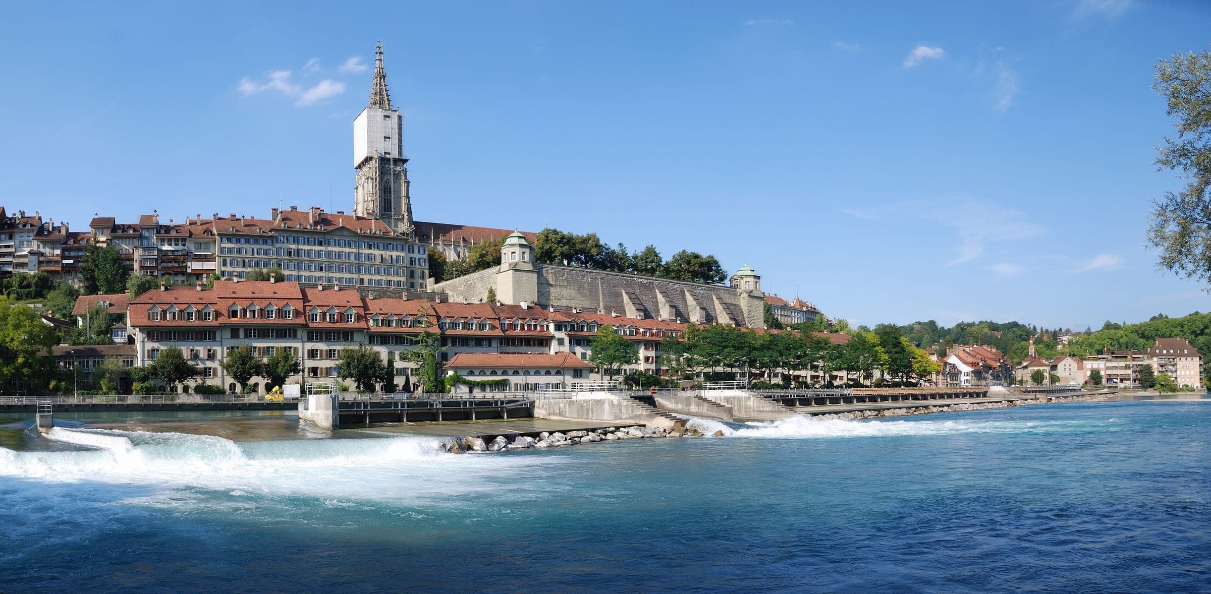 The Aare spills over the weir below Bern's old town with the Minster tower above the roofs