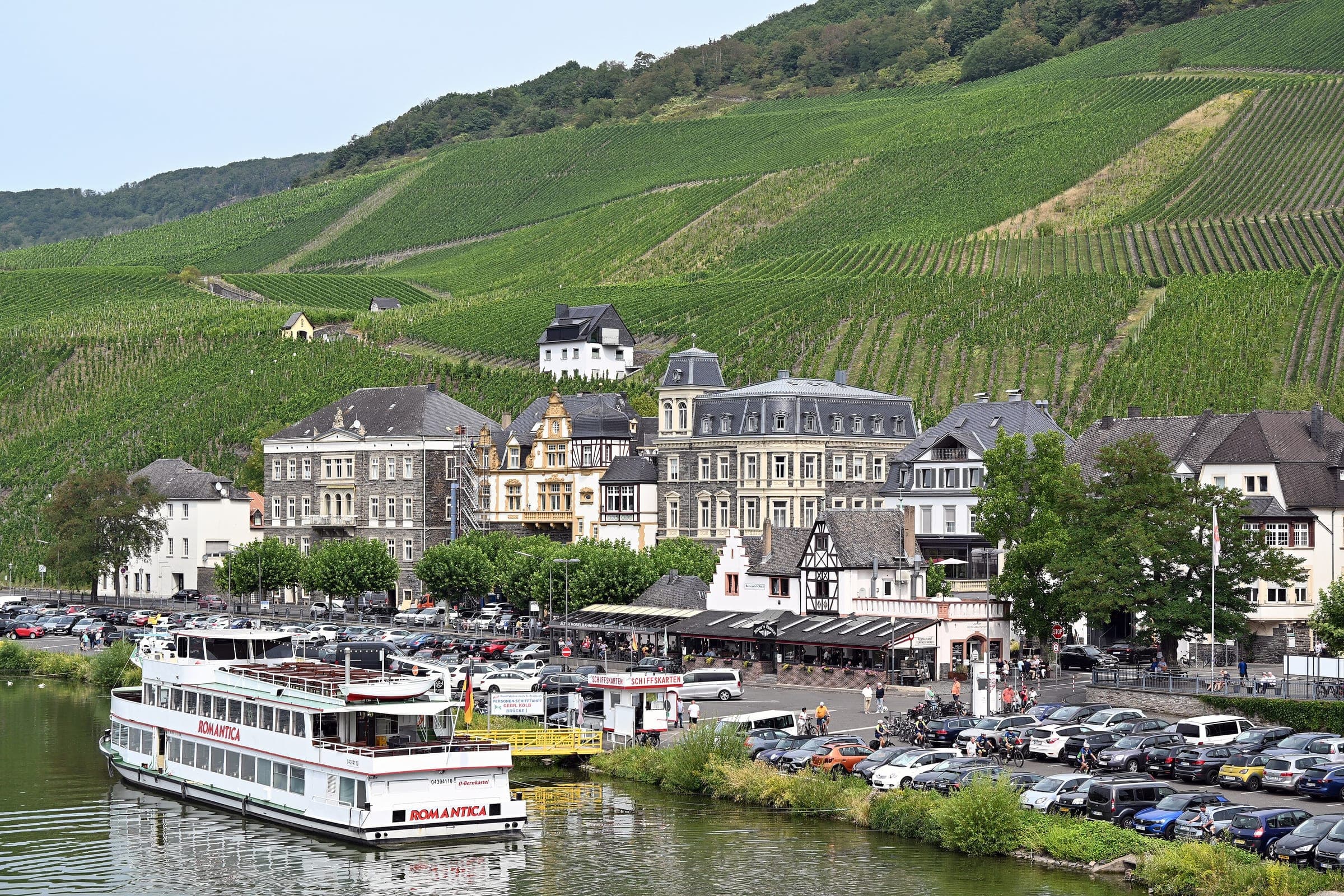 A river boat moors below Bernkastel's old town and its vineyard slopes seen from the Moselle bridge