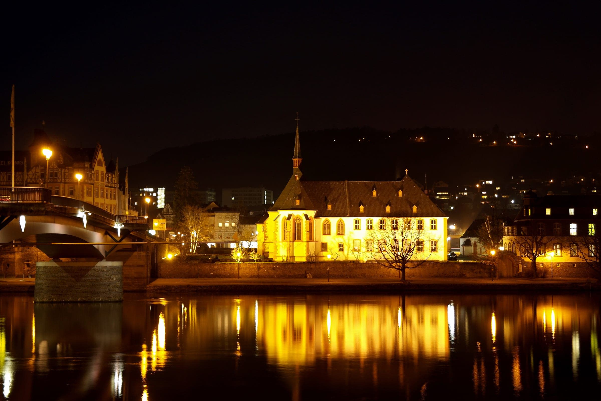 The St Nikolaus hospital in Kues and the Moselle bridge reflect in the river at night