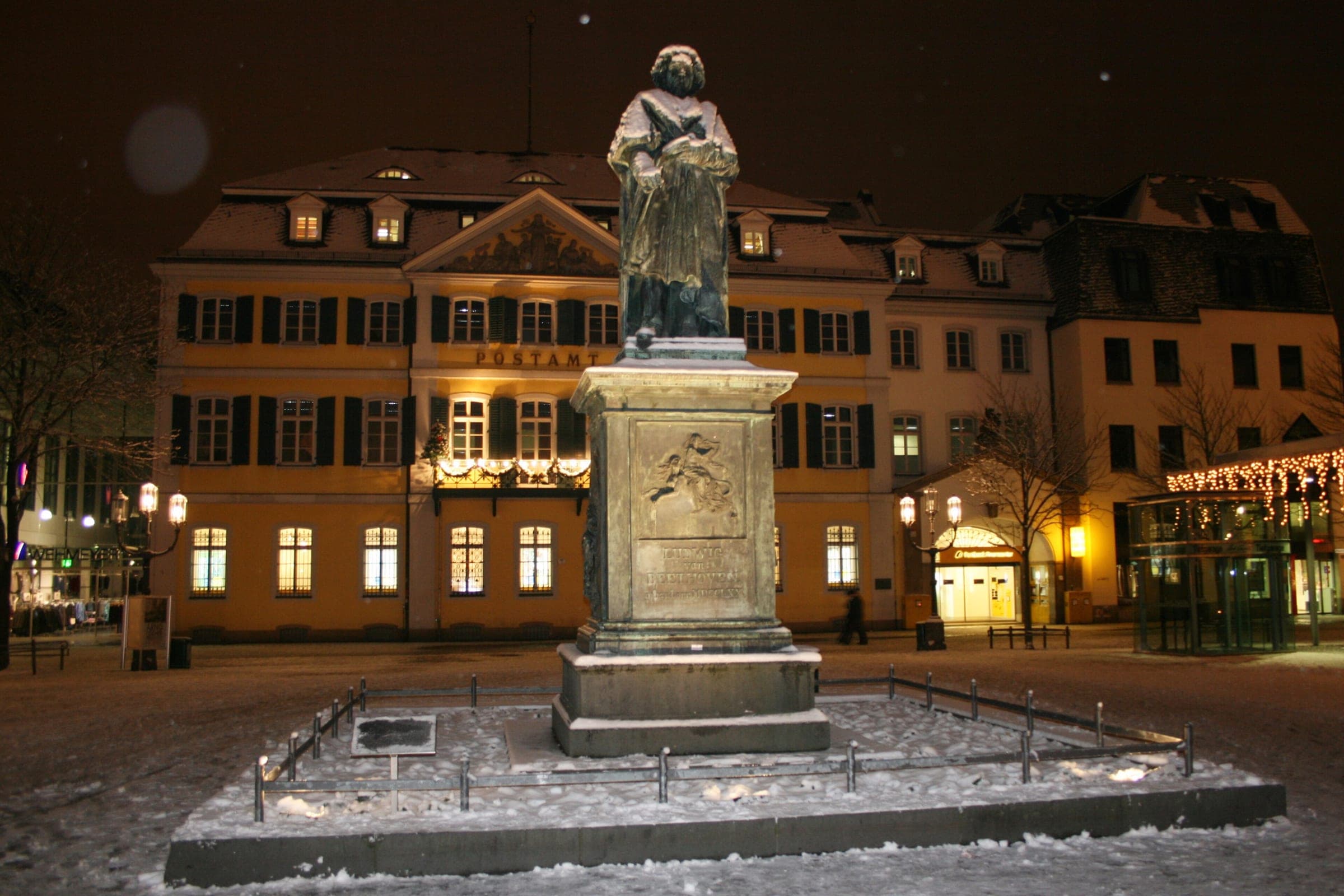 Fresh snow lies around the Beethoven monument on Bonn's Münsterplatz on a winter night
