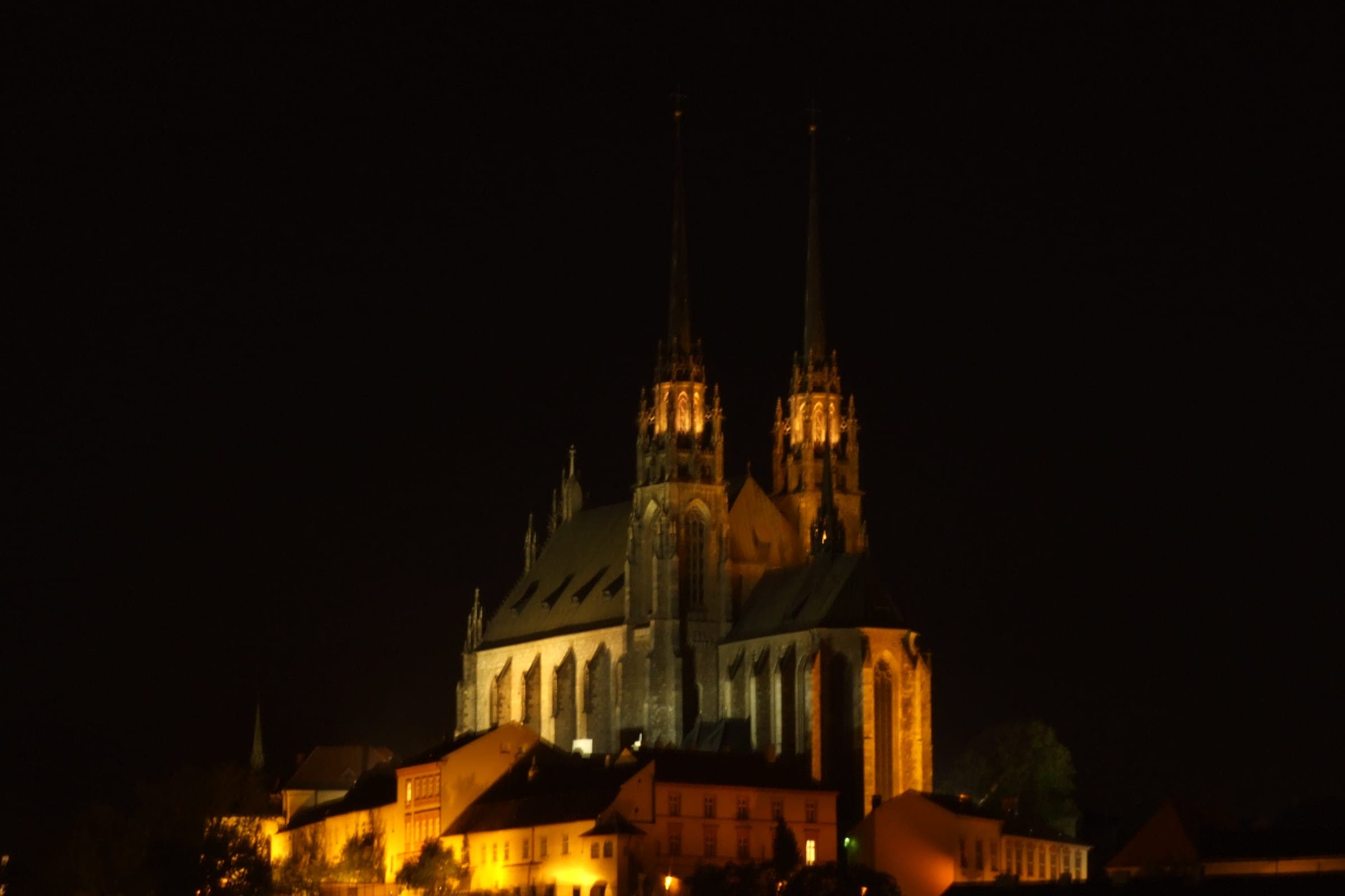 The floodlit Cathedral of Saints Peter and Paul crowns Petrov hill above the old town of Brno at night.