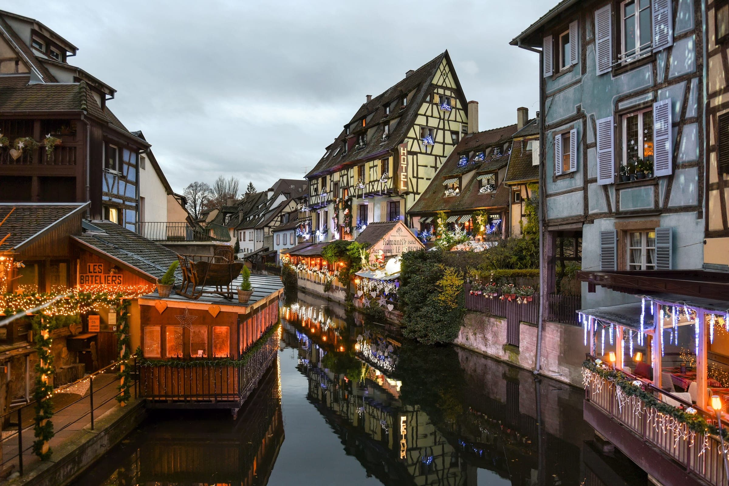 Half-timbered houses and lit terraces line the Lauch canal in Colmar's Petite Venise on a December afternoon.
