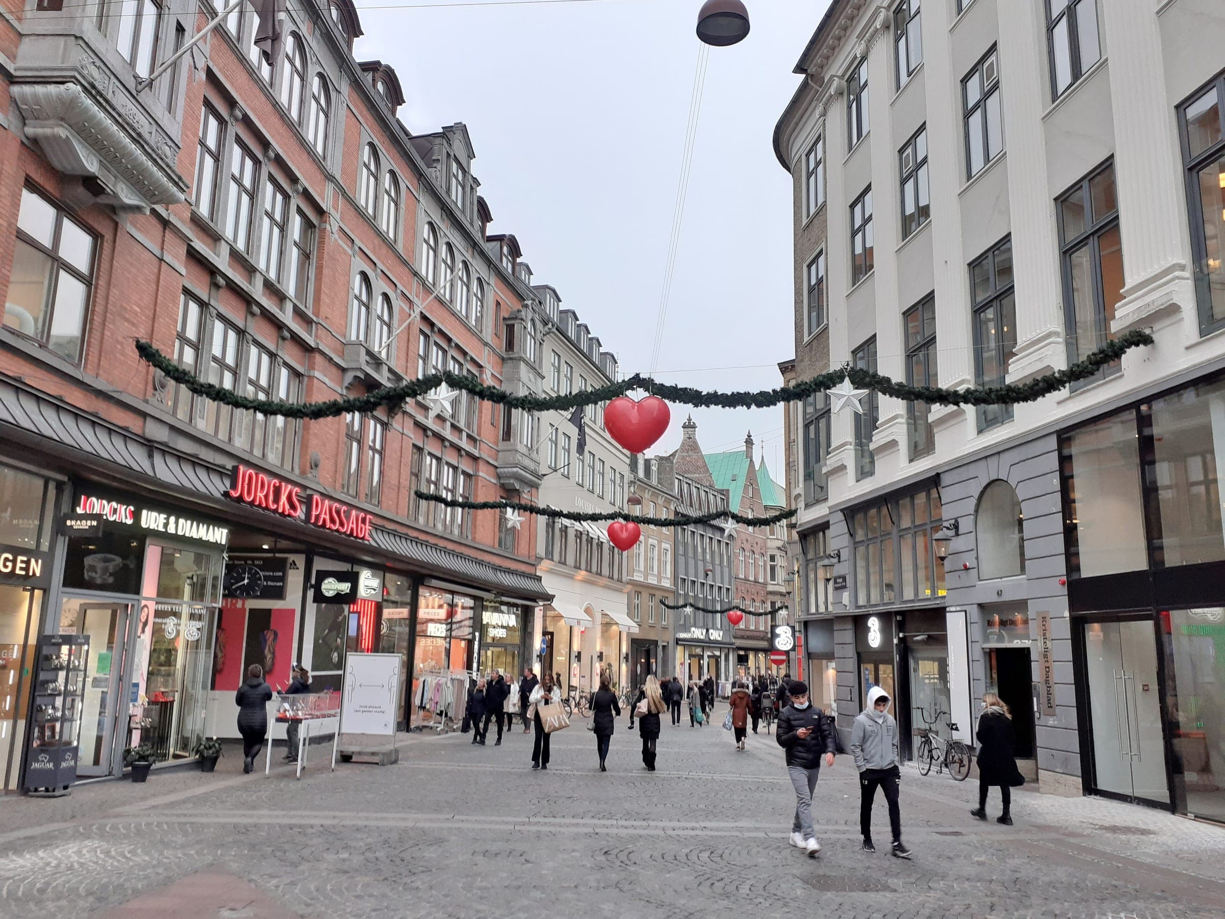 Garlands and red hearts hang over Vimmelskaftet on Strøget in Copenhagen as shoppers walk below.