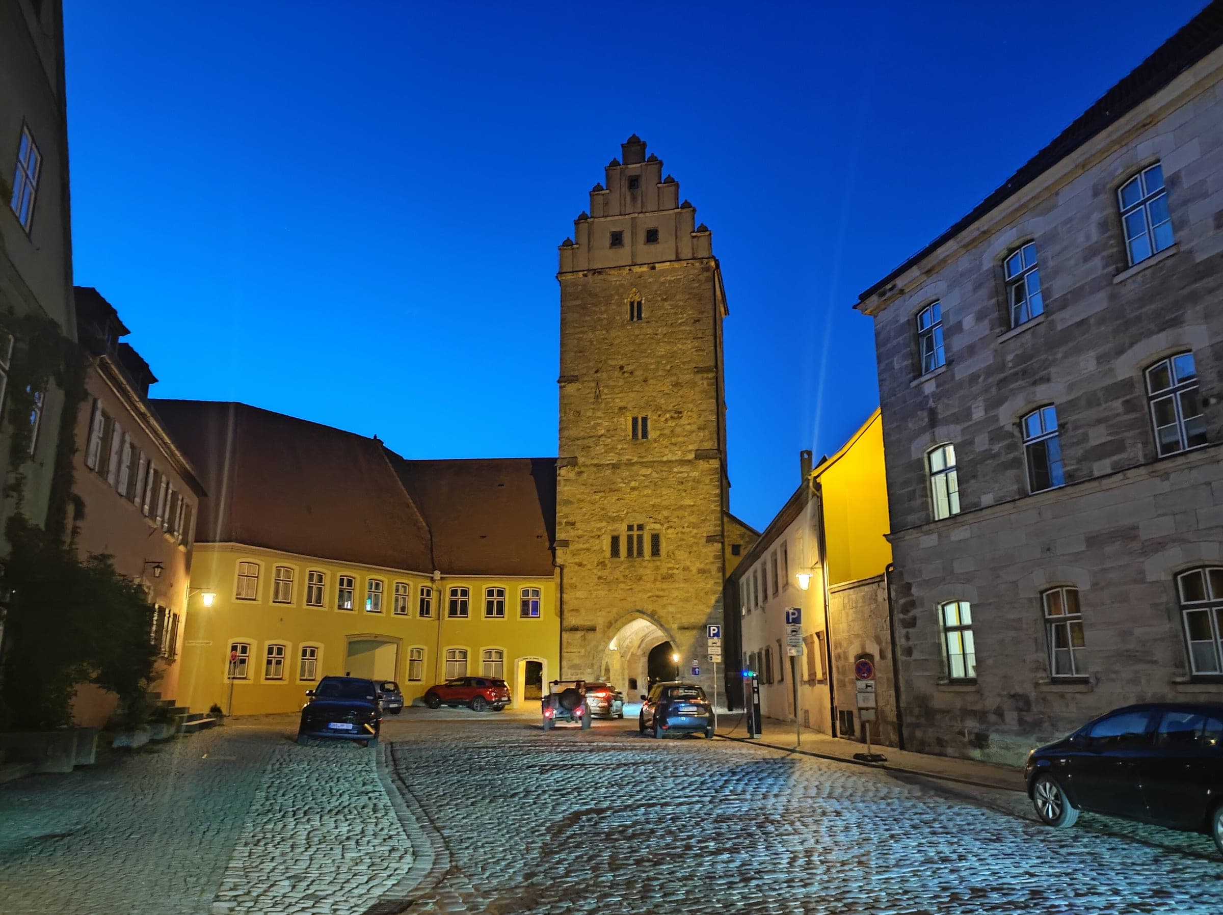 The stepped gable of the Rothenburger Tor rises over a cobbled street in Dinkelsbühl at blue hour
